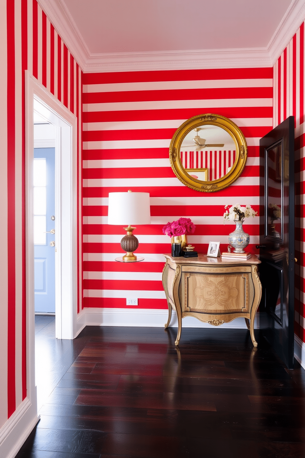 A striking foyer adorned with bold red and white striped wallpaper creates an inviting atmosphere. The floor is finished with dark hardwood, contrasting beautifully with the vibrant walls and enhancing the overall elegance of the space. An antique console table sits against the wall, topped with a chic lamp and a few curated decorative items. A round mirror with a gold frame hangs above the table, reflecting light and adding depth to the foyer.