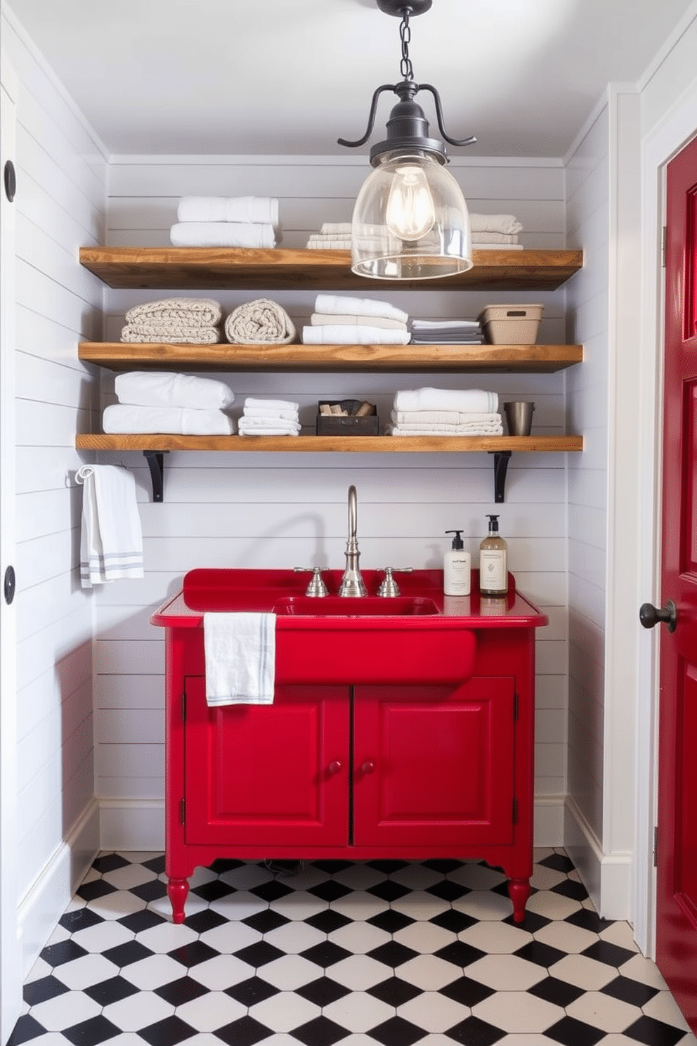 A vintage red laundry sink with a sleek modern faucet is the focal point of the room. Surrounding the sink, the walls are adorned with white shiplap, complemented by rustic wooden shelving that holds neatly folded towels and laundry essentials. The flooring features a classic black and white checkered pattern, adding a touch of timeless elegance. Soft, ambient lighting from a vintage-style pendant fixture illuminates the space, creating a warm and inviting atmosphere.