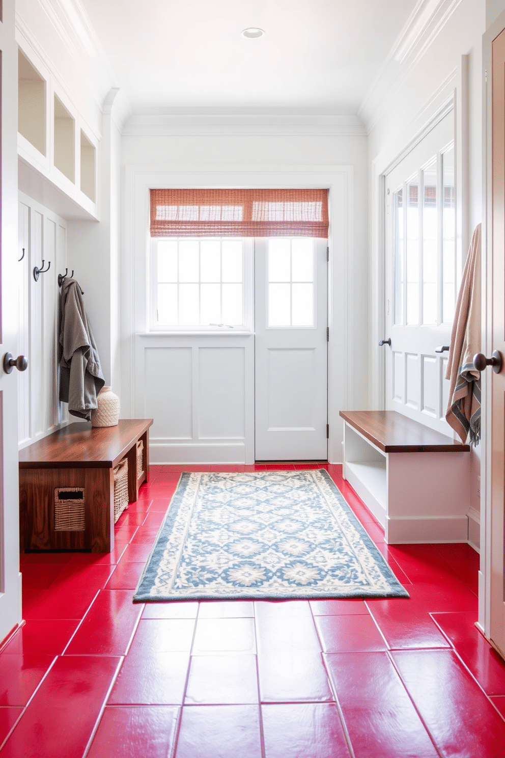 A striking mudroom featuring red tile flooring that creates a bold statement. The space is designed with built-in wooden benches and hooks for coats, complemented by bright white walls that enhance the vibrant flooring. Natural light floods the area through a large window, illuminating a stylish area rug that adds warmth. Decorative baskets are neatly arranged under the bench, providing both functionality and a pop of texture.