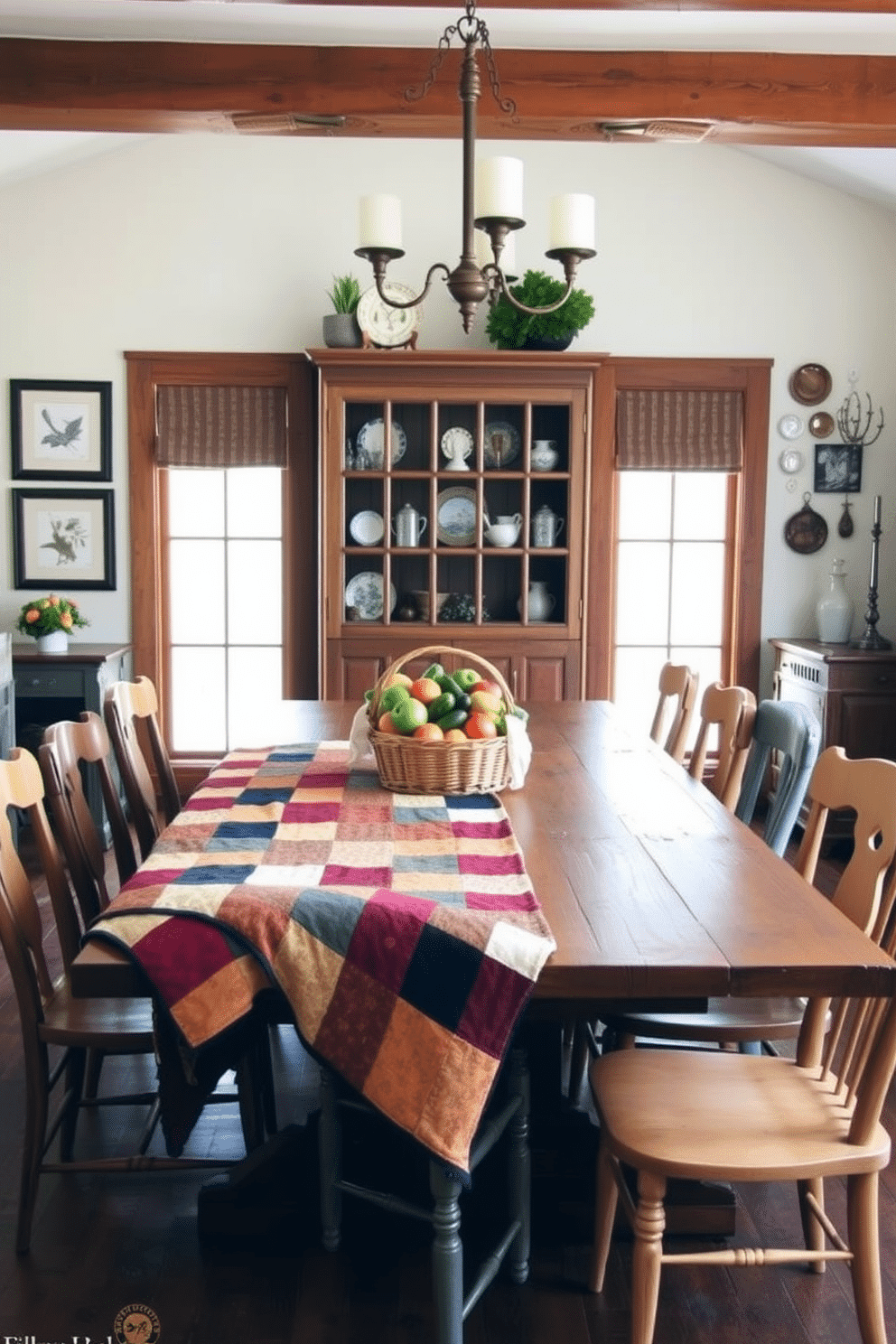 A rustic dining room features a large wooden table with a patchwork quilt draped across it, adding warmth and texture to the space. Surrounding the table are mismatched chairs, each with a unique finish, creating an inviting and eclectic atmosphere. The walls are adorned with vintage farmhouse decor, including framed botanical prints and a collection of antique plates. A woven basket filled with fresh produce sits as a centerpiece, enhancing the room's cozy and rustic charm.