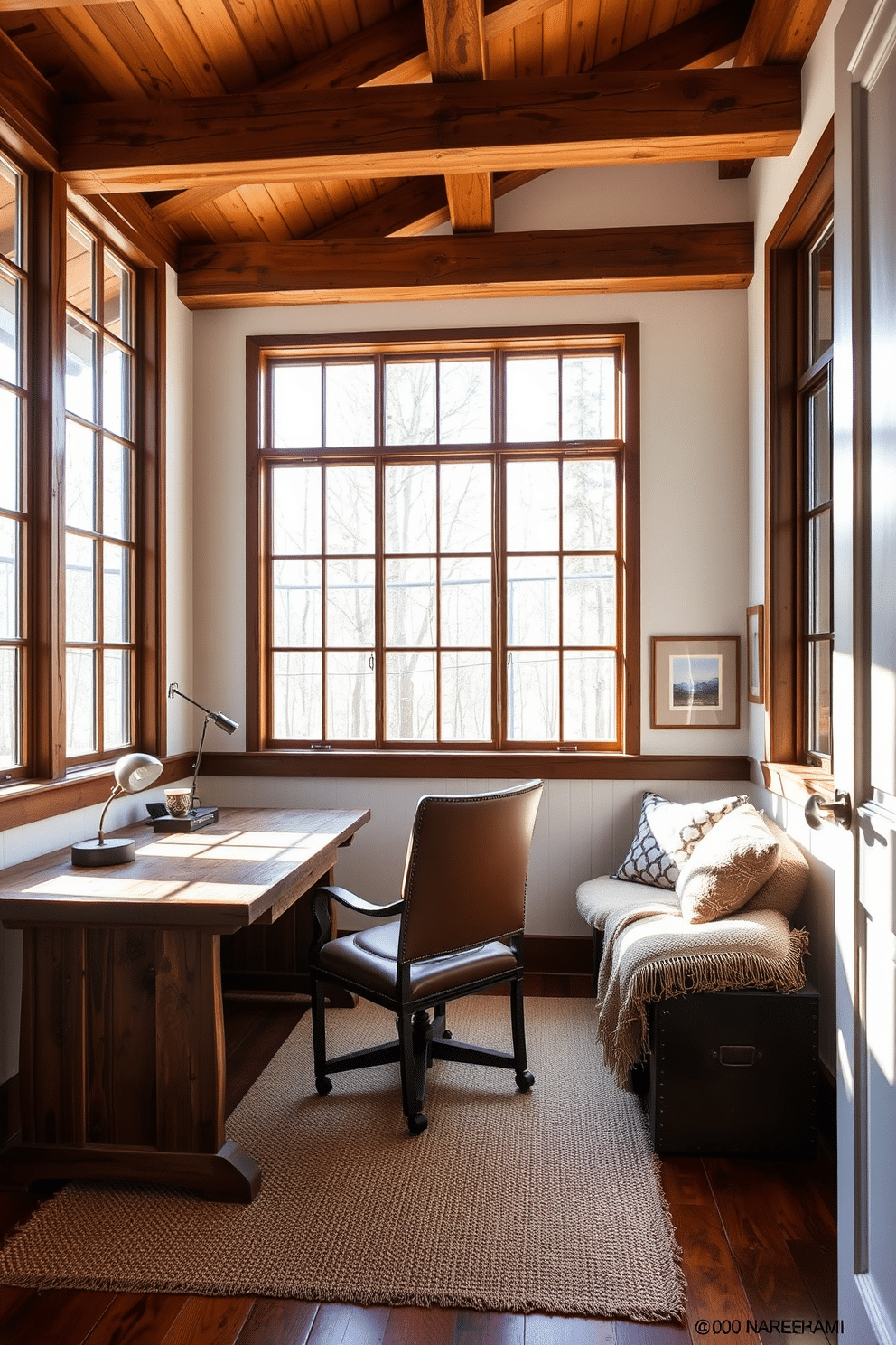 A rustic home office bathed in natural light streams through large, floor-to-ceiling windows, illuminating the warm wooden beams overhead. The room features a reclaimed wood desk paired with a vintage leather chair, complemented by a cozy reading nook adorned with plush cushions and a woven throw.