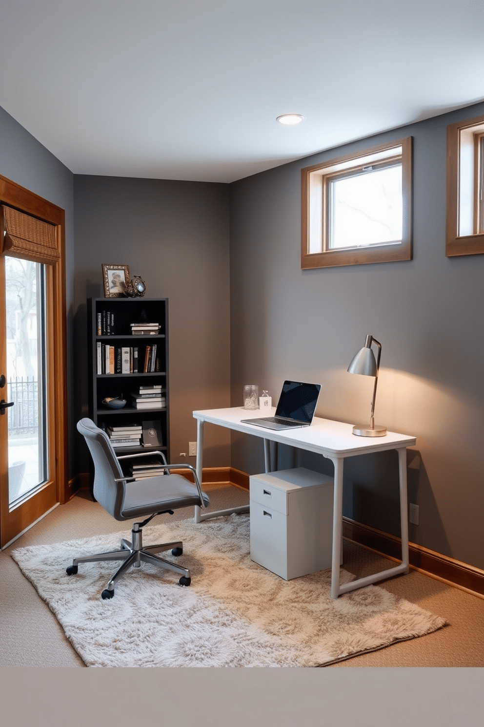 A cozy basement workspace features a sleek, modern desk positioned against a wall, illuminated by a stylish desk lamp. The walls are painted in a soft gray, complemented by warm wood accents and a plush area rug underfoot. To the left of the desk, a comfortable chair invites long hours of study or work, while a small bookshelf filled with books and decorative items adds character to the space. Large windows allow natural light to flood in, creating an inviting atmosphere that balances functionality and comfort.