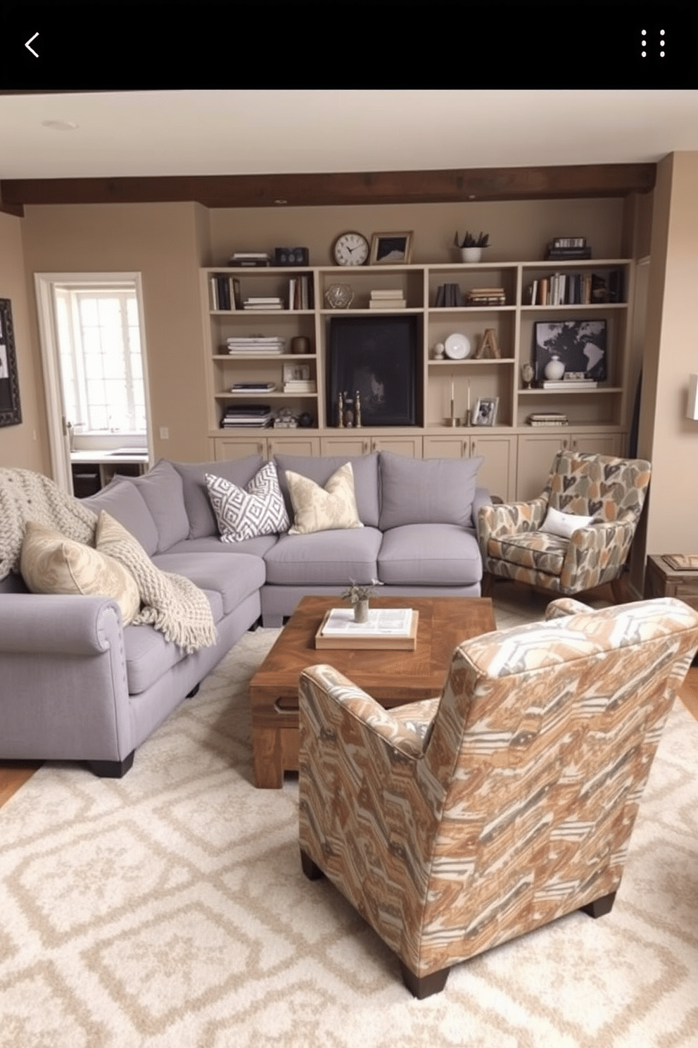 A cozy family room with a plush sectional sofa in a soft gray fabric, complemented by a chunky knit throw blanket and a mix of patterned pillows. The walls are painted a warm beige, and a large area rug with a geometric design anchors the space, while a wooden coffee table with a distressed finish adds rustic charm. In one corner, a stylish armchair upholstered in a vibrant fabric offers a pop of color, paired with a sleek floor lamp for reading. Shelves filled with books and decorative items line the walls, creating a welcoming atmosphere for family gatherings and relaxation.