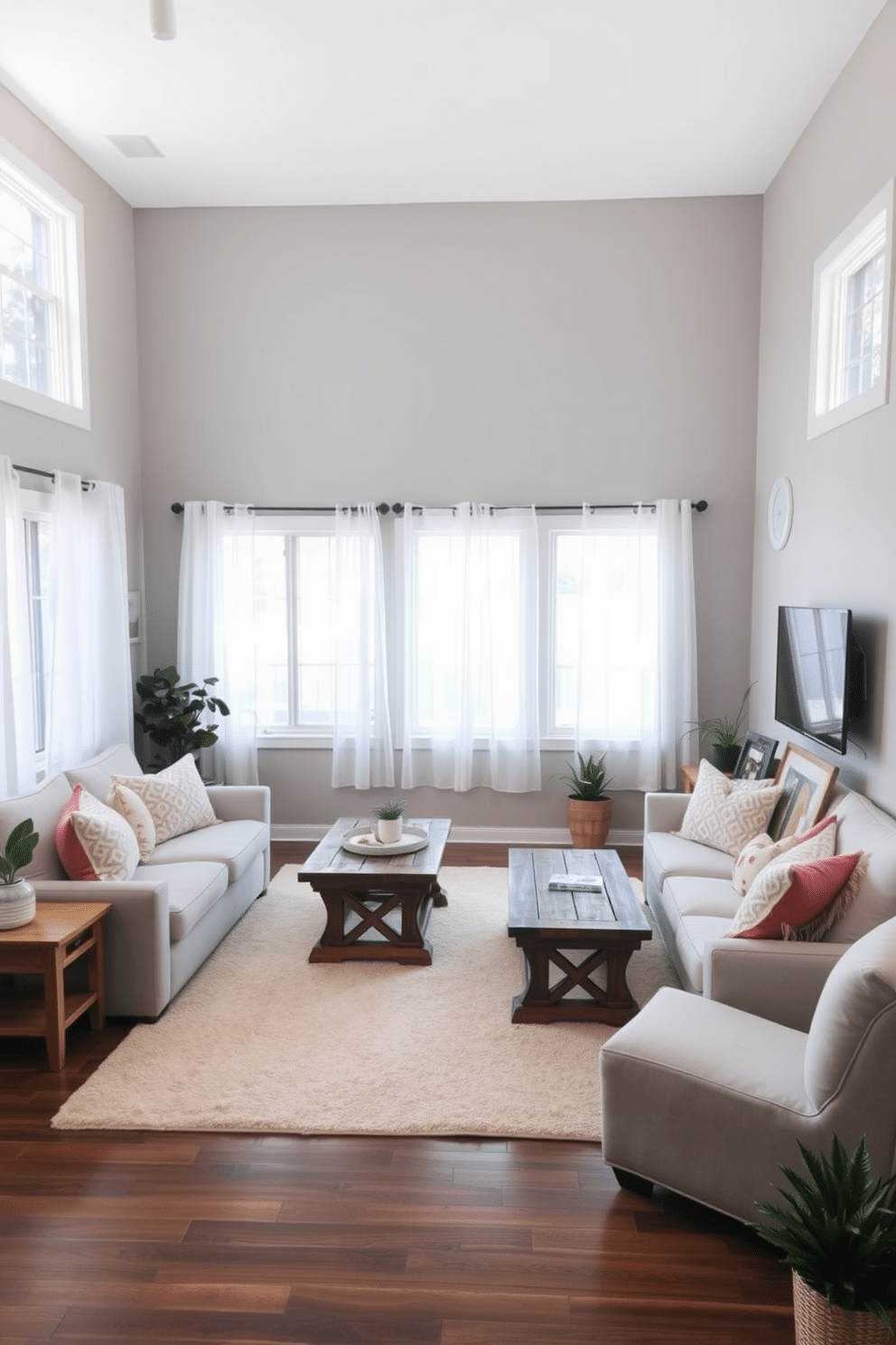 A cozy family room with soft, muted colors that create a calming atmosphere. The space features a plush, light gray sectional sofa adorned with pastel throw pillows, complemented by a cream area rug beneath a rustic wooden coffee table. Natural light floods the room through large windows dressed with sheer white curtains. A simple entertainment unit holds a flat-screen TV, while a few framed family photos and potted plants add warmth and personality to the design.