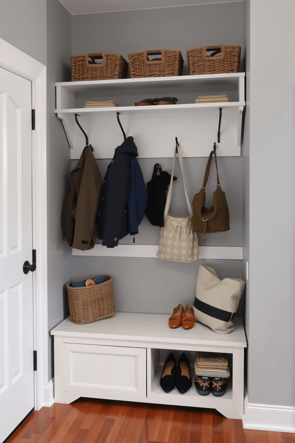 A functional coat rack with a shelf above is designed to maximize space and organization. The coat rack features sturdy hooks for hanging jackets and bags, while the shelf above holds decorative baskets for storing shoes and accessories. The mudroom is styled with a neutral color palette, incorporating soft gray walls and a warm wood floor. A bench with built-in storage sits below the coat rack, providing a cozy spot to sit while putting on or taking off shoes.