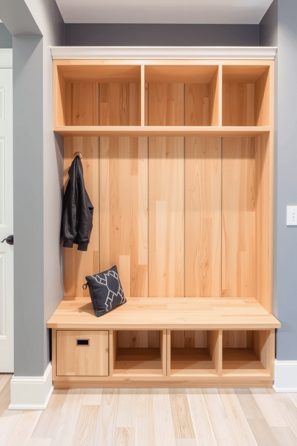 A simple mudroom design featuring built-in cubbies for organized storage. The cubbies are crafted from light wood, providing a warm contrast to the cool gray walls, and are topped with a sleek bench for added functionality.