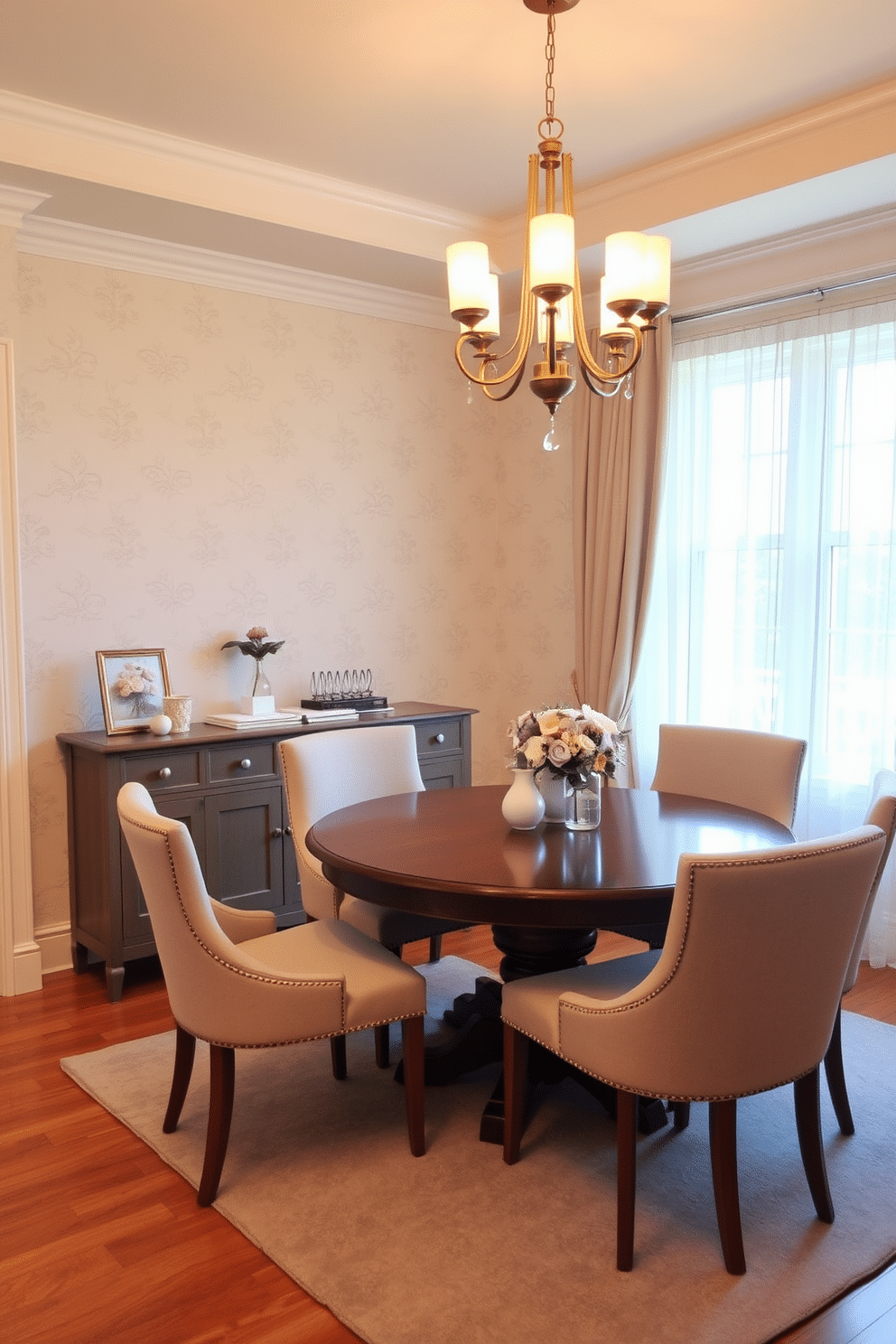 A cozy dining room featuring a round wooden table surrounded by upholstered chairs in soft pastel colors. The walls are adorned with subtle floral wallpaper, and a statement chandelier hangs above the table, providing warm, inviting light. In one corner, a small sideboard displays elegant dinnerware and decorative accents. A large window allows natural light to flood the space, complemented by sheer curtains that add a touch of softness.