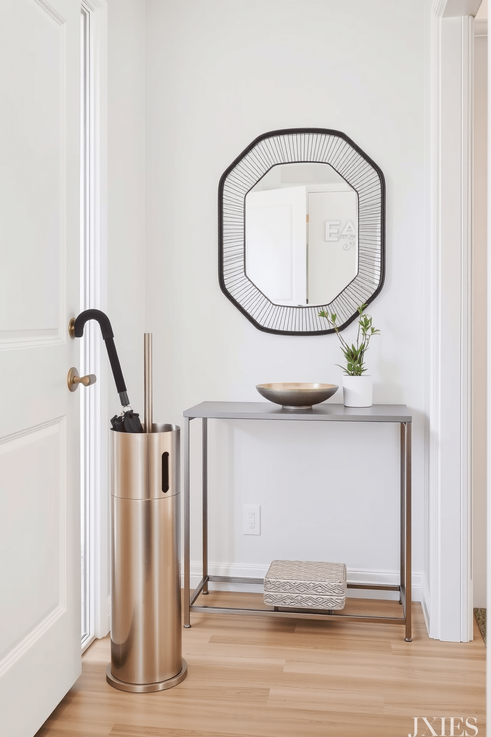 A chic umbrella stand made of brushed metal stands elegantly by the door, complementing the modern aesthetic of the space. The entryway features a minimalist console table with a sleek design, adorned with a small potted plant and a stylish bowl for keys. The walls are painted in a soft, neutral tone, enhancing the bright and airy feel of the small entryway. A decorative mirror above the console reflects light, making the area feel more spacious and inviting.