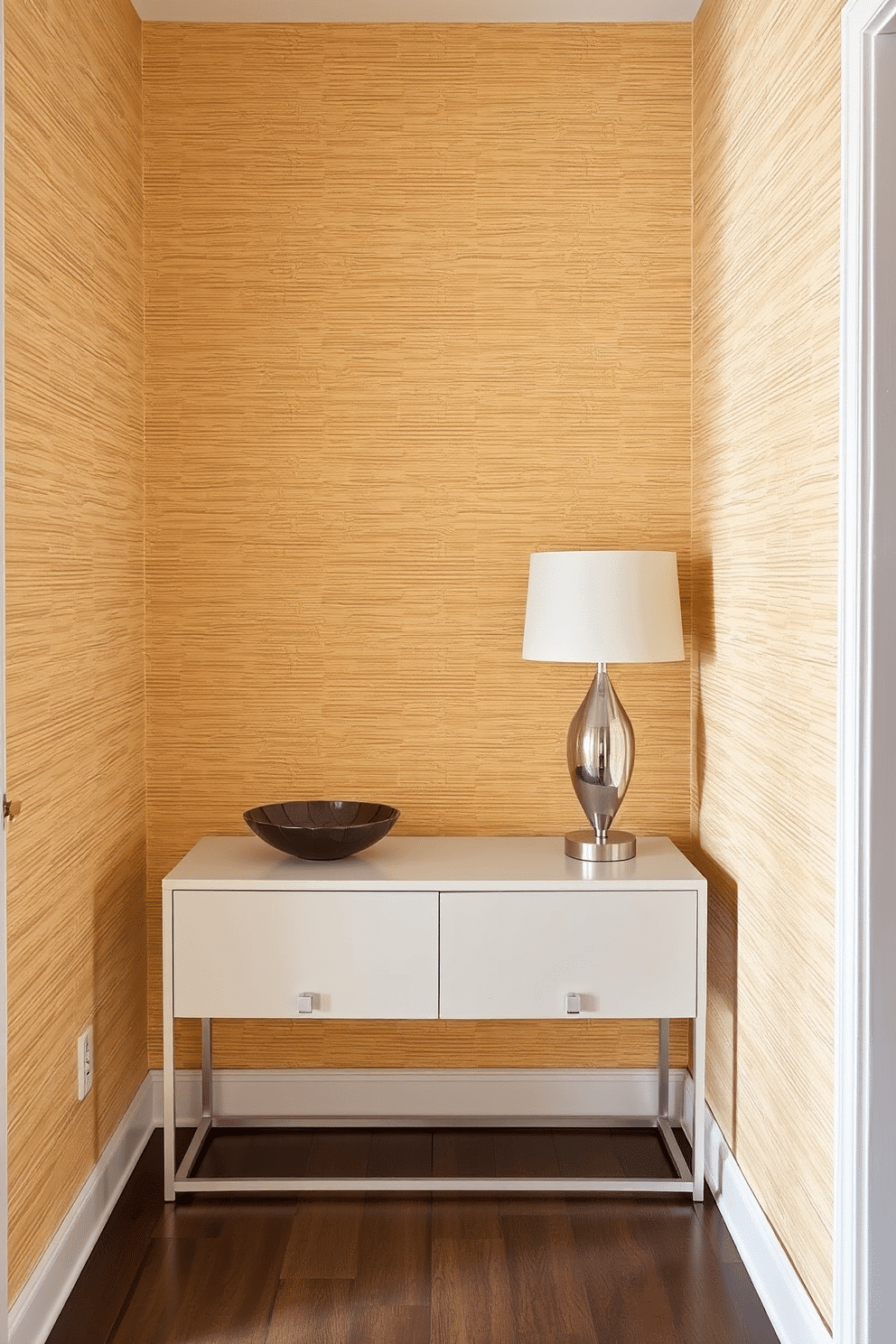 A small entryway features textured wallpaper in a warm beige tone, adding depth and a cozy atmosphere. A sleek console table with a minimalist design sits against the wall, adorned with a decorative bowl and a stylish lamp.