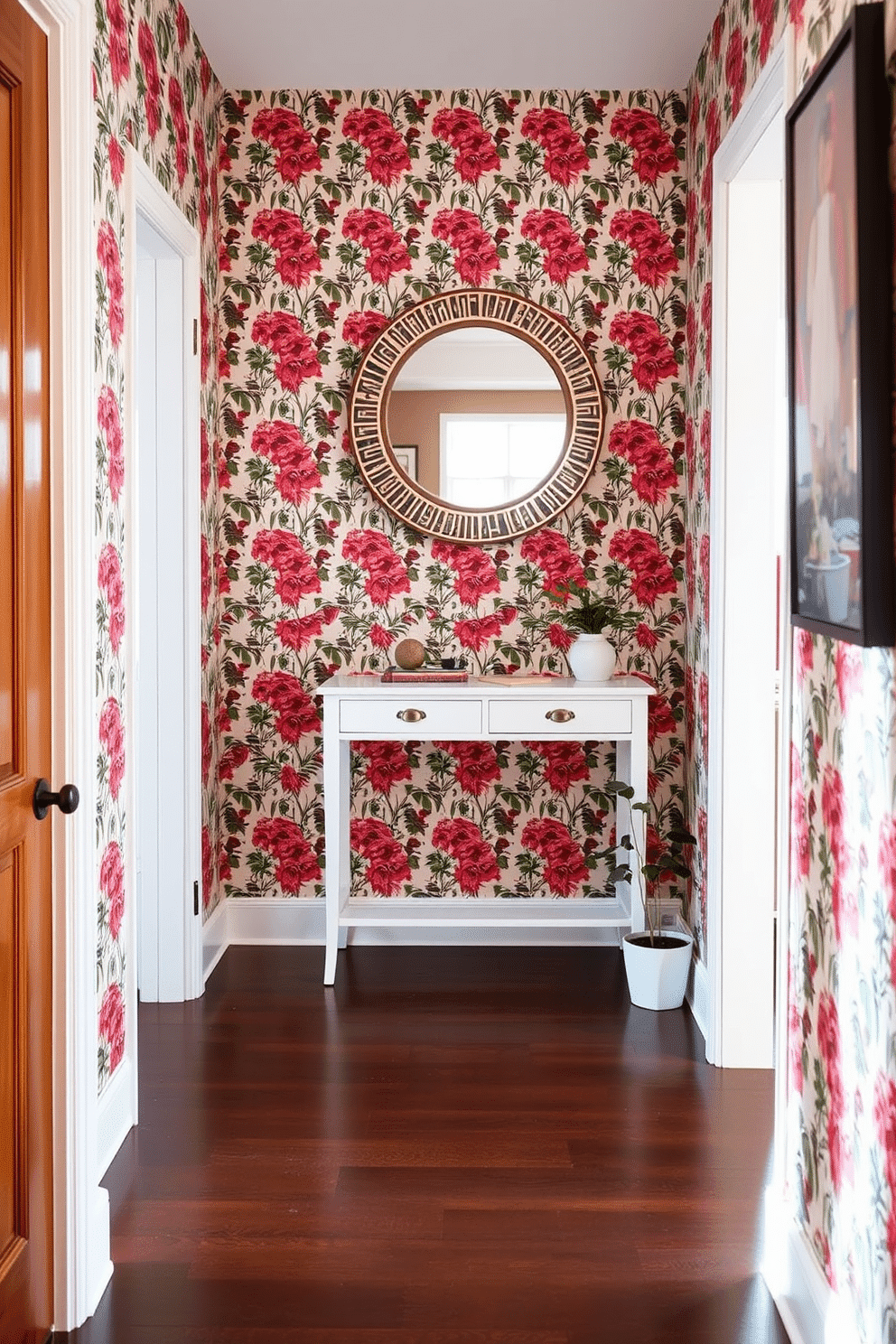 A small entryway adorned with bold wallpaper featuring a vibrant floral pattern, immediately drawing attention and setting a lively tone for the space. The flooring is a sleek, dark wood that contrasts beautifully with the wallpaper, while a minimalist console table in white offers a practical surface for keys and mail. A round mirror with a decorative frame hangs above the console table, enhancing the sense of depth and light in the entryway. To the side, a small potted plant adds a touch of greenery, creating an inviting atmosphere as guests enter the home.