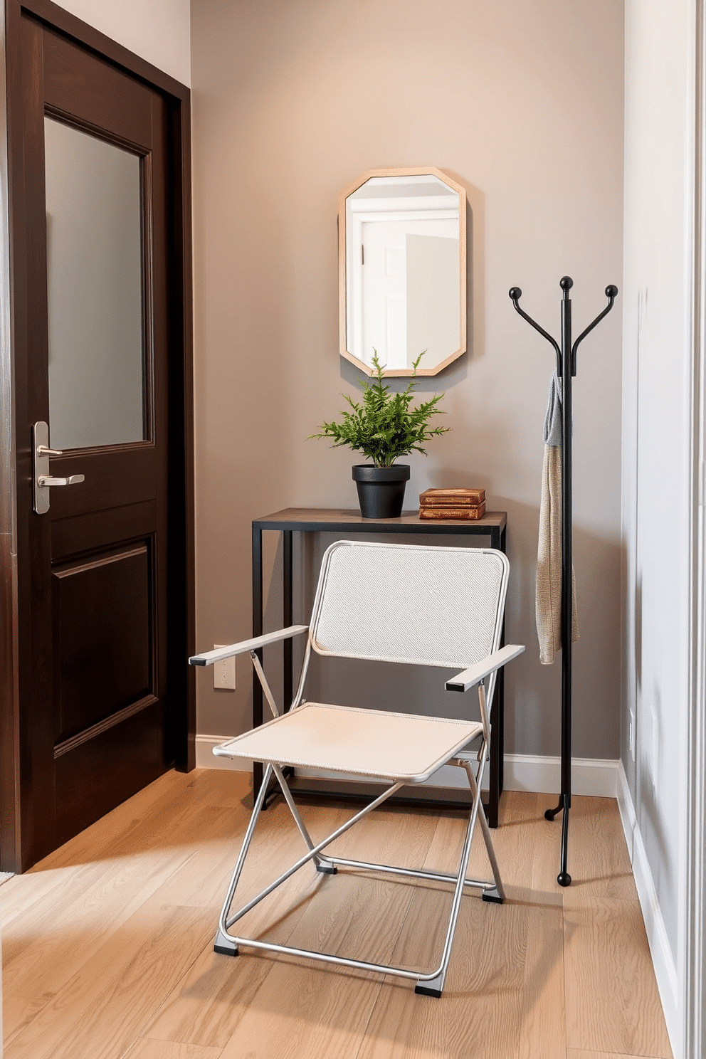 A sleek space-saving folding chair is elegantly positioned against the wall, crafted from lightweight metal with a minimalist design. The chair features a soft, cushioned seat in a neutral fabric, making it both practical and stylish for any small space. The foyer showcases a compact design with a narrow console table against the wall, adorned with a small decorative mirror above it. A potted plant sits on the table, adding a touch of greenery, while a stylish coat rack stands nearby for convenience and organization.