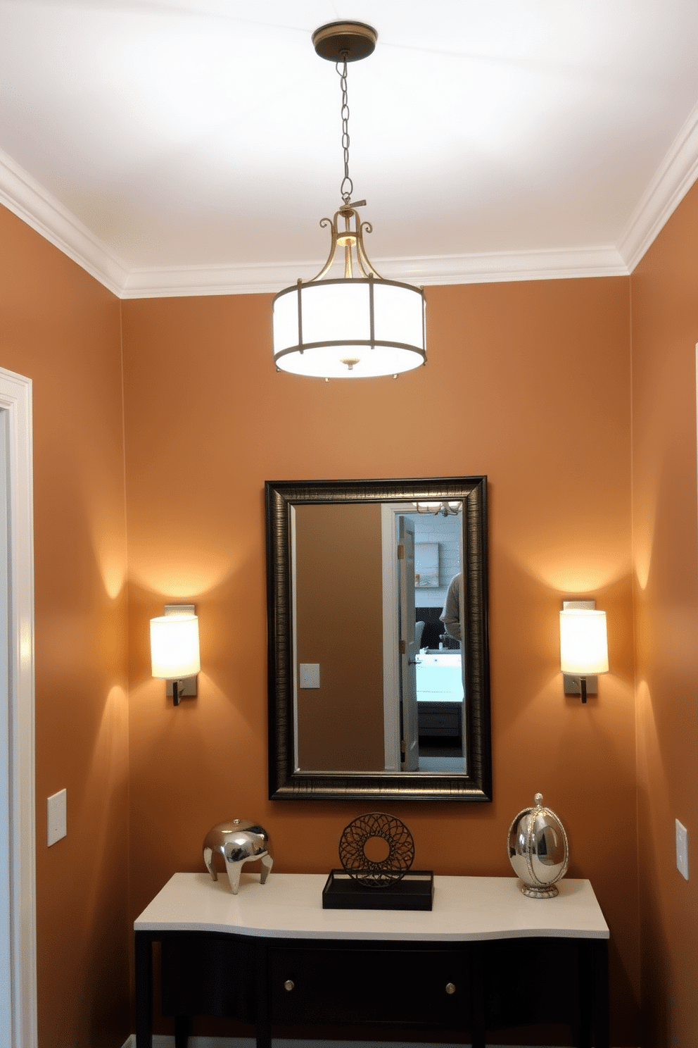 A small foyer with layered lighting creates a welcoming atmosphere. A chic pendant light hangs from the ceiling, complemented by wall sconces that provide soft illumination. The walls are painted in a warm, neutral tone, enhancing the natural light that filters through the space. A stylish console table with decorative elements and a mirror above it adds depth and functionality to the design.