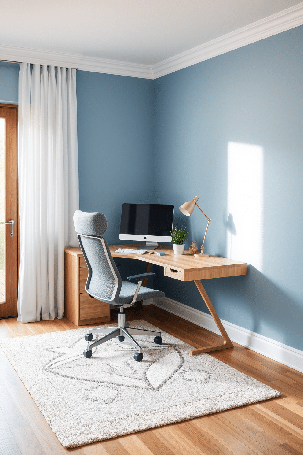 A cozy home office design featuring a corner desk made of light oak wood, paired with an ergonomic chair in a soft gray fabric. The walls are painted in a calming blue hue, and a large window allows natural light to flood the space, complemented by sheer white curtains. On the desk, a sleek computer monitor is positioned alongside a potted plant and a stylish desk lamp with a warm glow. The floor is adorned with a plush area rug in neutral tones, adding comfort and warmth to the overall aesthetic.