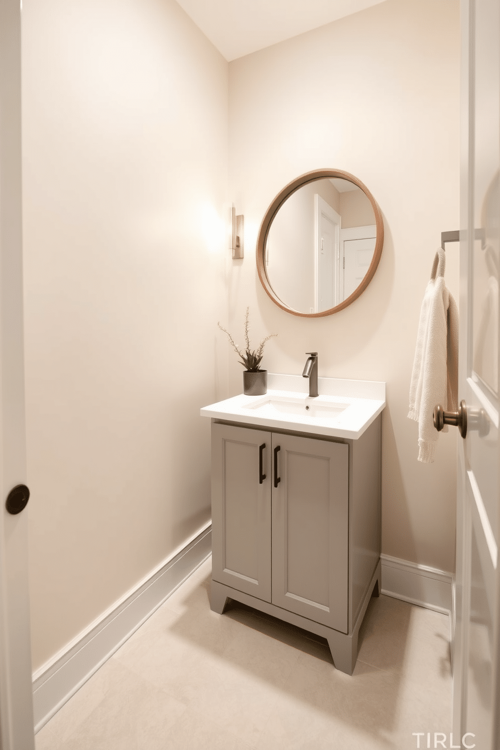 A small powder room designed with neutral tones to create a calming atmosphere. The walls are painted in soft beige, complemented by a light gray vanity with a white quartz countertop. A round mirror with a minimalist wooden frame hangs above the sink, reflecting the warm light from a stylish wall sconce. The floor features large, light-colored tiles, and a small potted plant adds a touch of greenery to the space.