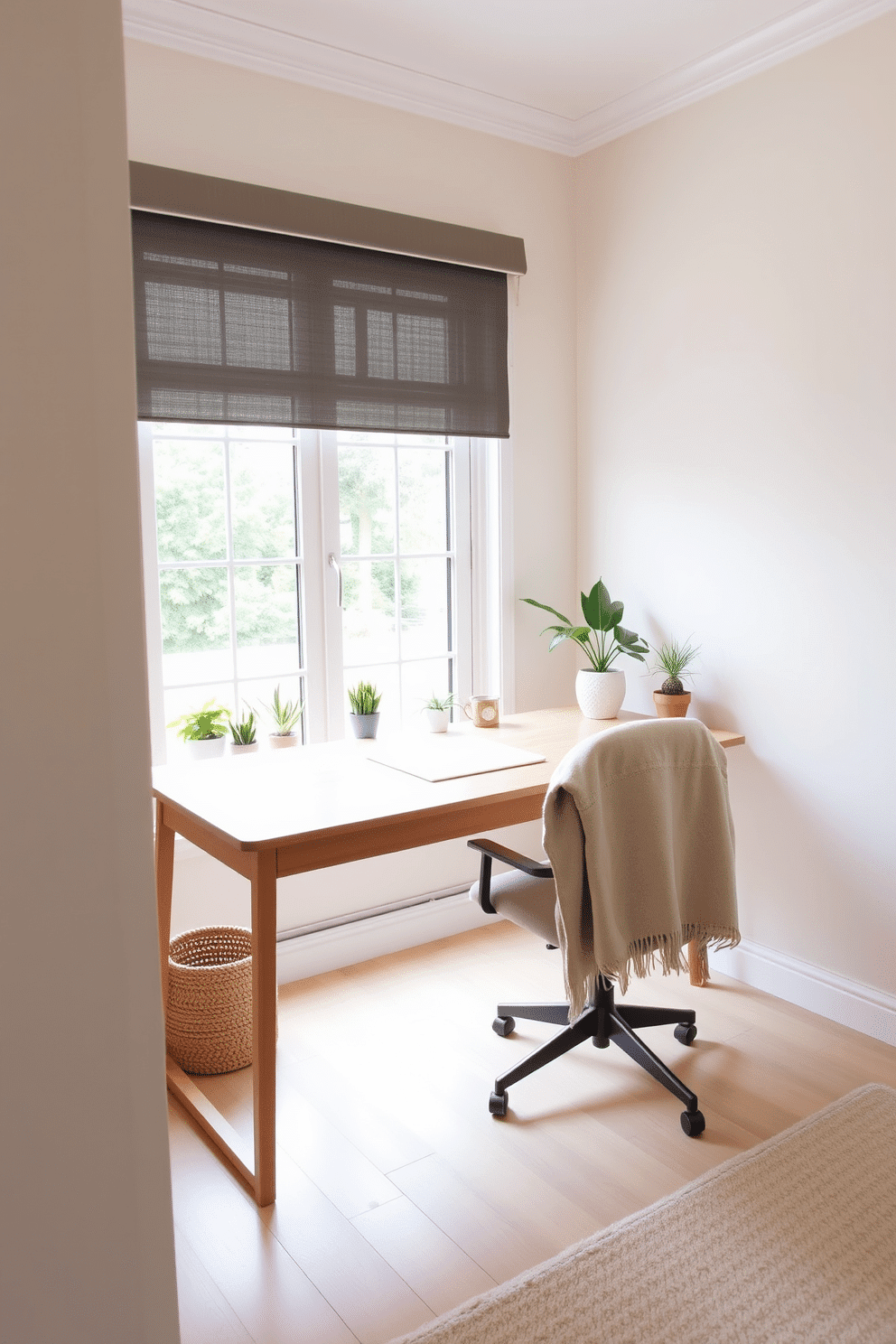 A cozy home office space featuring a light wooden desk with a sleek design. A comfortable chair is positioned at the desk, adorned with a soft throw blanket draped over one arm. The walls are painted in a soft pastel hue, creating a calming atmosphere. A large window allows natural light to flood the room, complemented by a few potted plants on the windowsill.