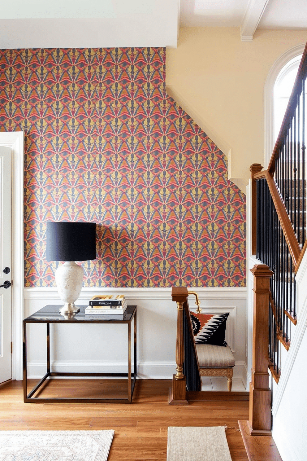 A bold accent wall features an intricate geometric wallpaper design in vibrant colors, creating a striking focal point in the room. Complementing the wall, a sleek console table sits below, adorned with a statement lamp and decorative accessories that enhance the overall aesthetic. The staircase landing is designed with a blend of functionality and style, showcasing a cozy reading nook with a plush armchair and a small bookshelf. Natural light floods the space through a nearby window, highlighting the elegant staircase railing and the rich wood tones of the landing.