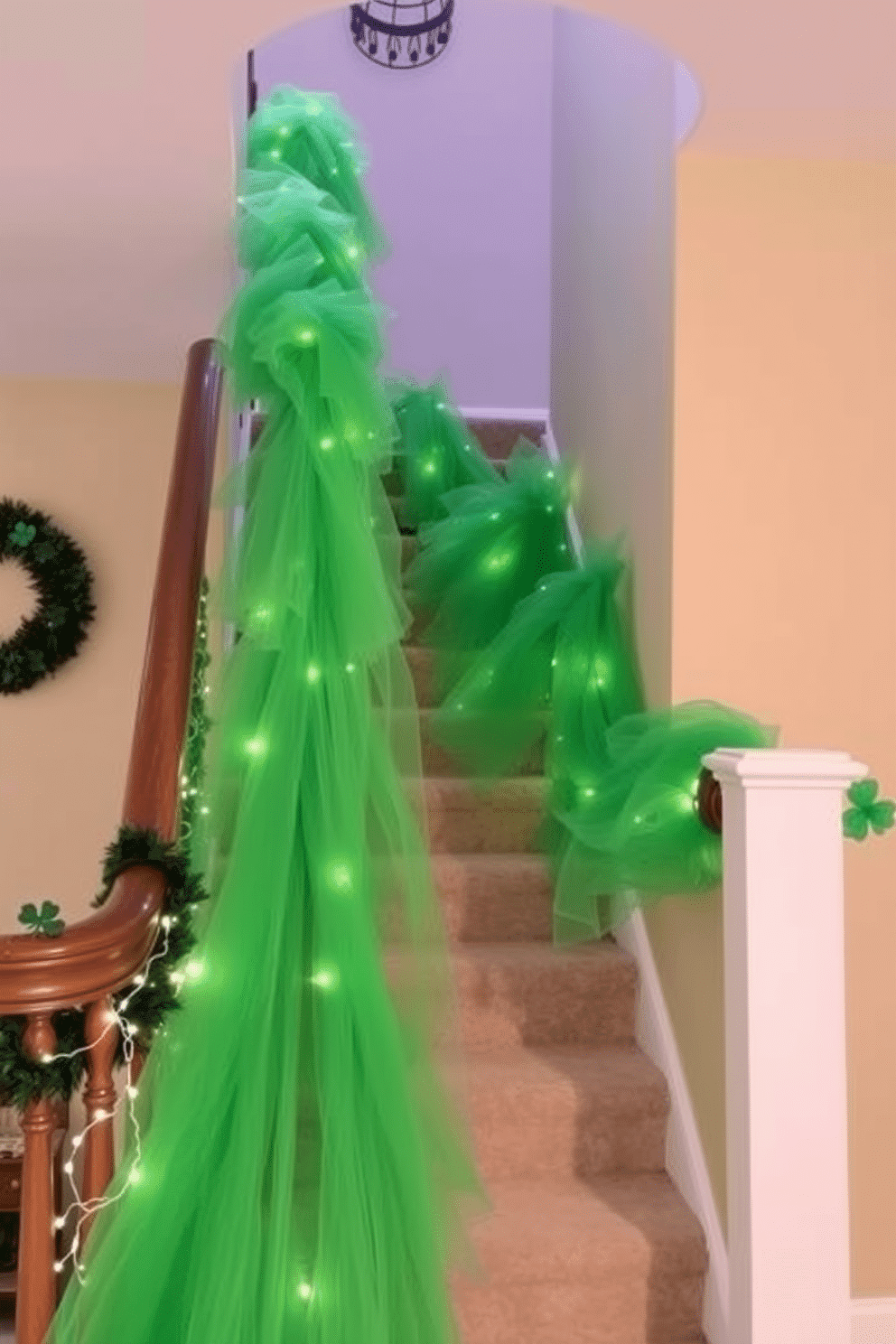 A whimsical staircase adorned with flowing green tulle, cascading elegantly from the banister. The tulle is complemented by festive St. Patrick's Day decorations, including shamrocks and twinkling fairy lights, creating a vibrant and inviting atmosphere.