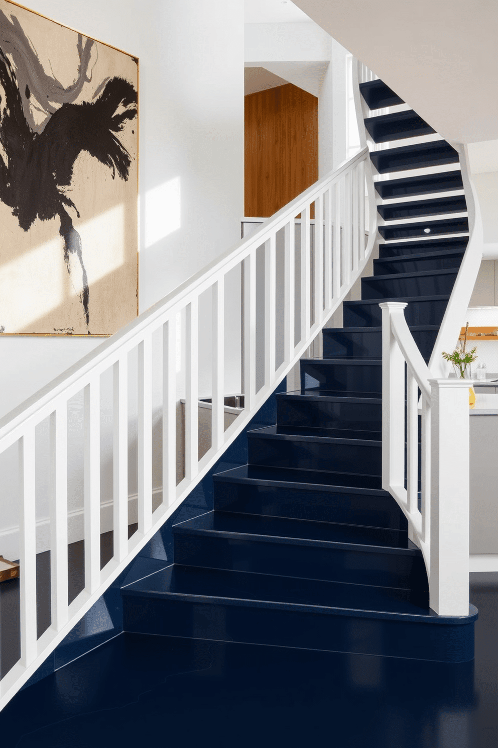 A modern staircase featuring a sleek design with contrasting colors, where the steps are a deep navy blue and the railing is a crisp white. The backdrop is adorned with a large abstract painting that complements the color scheme, creating a striking visual impact. In the kitchen, the staircase seamlessly integrates into the space, with open risers that allow natural light to filter through. The kitchen features a minimalist aesthetic with high-gloss cabinetry in a light gray, paired with warm wooden accents for a cozy yet contemporary feel.