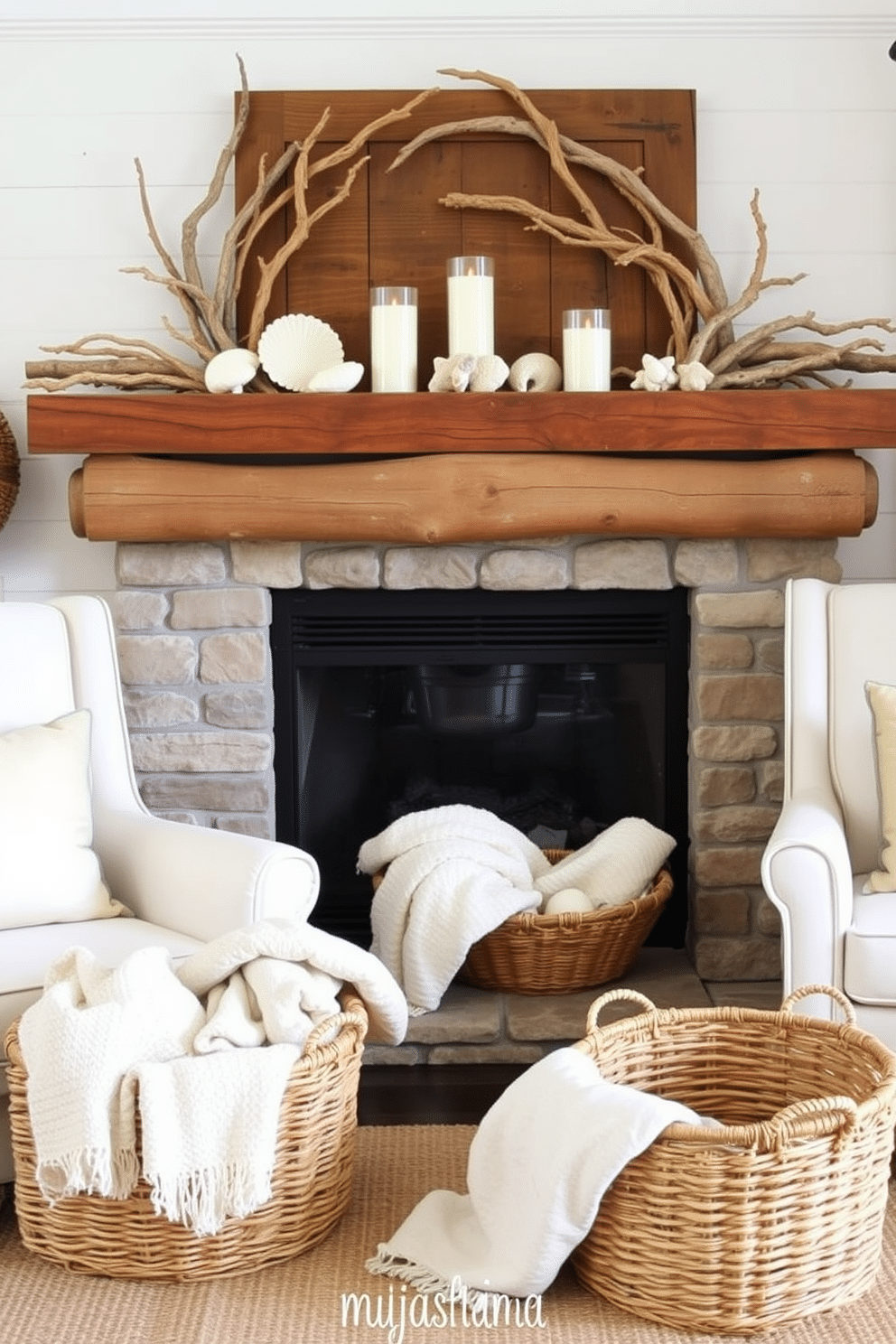 A cozy living room setting featuring a summer fireplace adorned with driftwood accents. The fireplace is surrounded by natural stone, and a rustic wooden mantel displays seasonal decor like seashells and candles. On either side of the fireplace, there are comfortable armchairs upholstered in light, airy fabrics. A woven basket filled with soft blankets sits nearby, inviting relaxation and warmth on cool summer evenings.