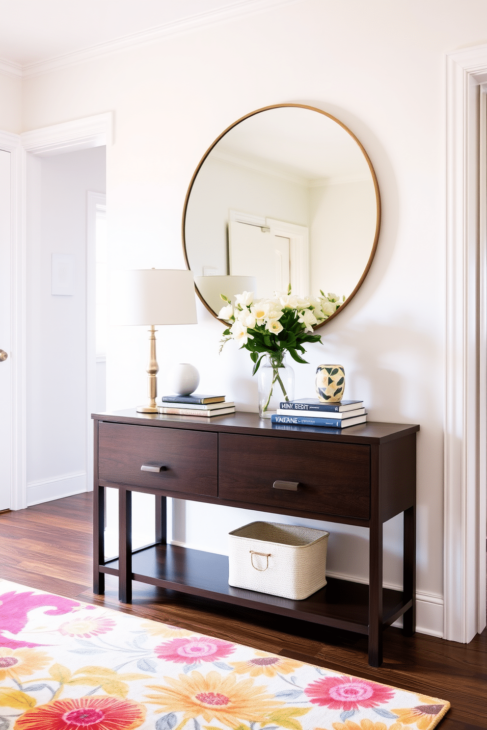 A stylish hallway features a sleek console table made of dark wood, providing both functionality and elegance. Above the table, a large round mirror reflects natural light, enhancing the space's brightness and depth. On the console table, a collection of decorative items including a vase of fresh flowers and a stack of art books adds a personal touch. The walls are adorned with light pastel colors, complemented by a runner rug in vibrant summer tones to bring warmth and cheer to the hallway.