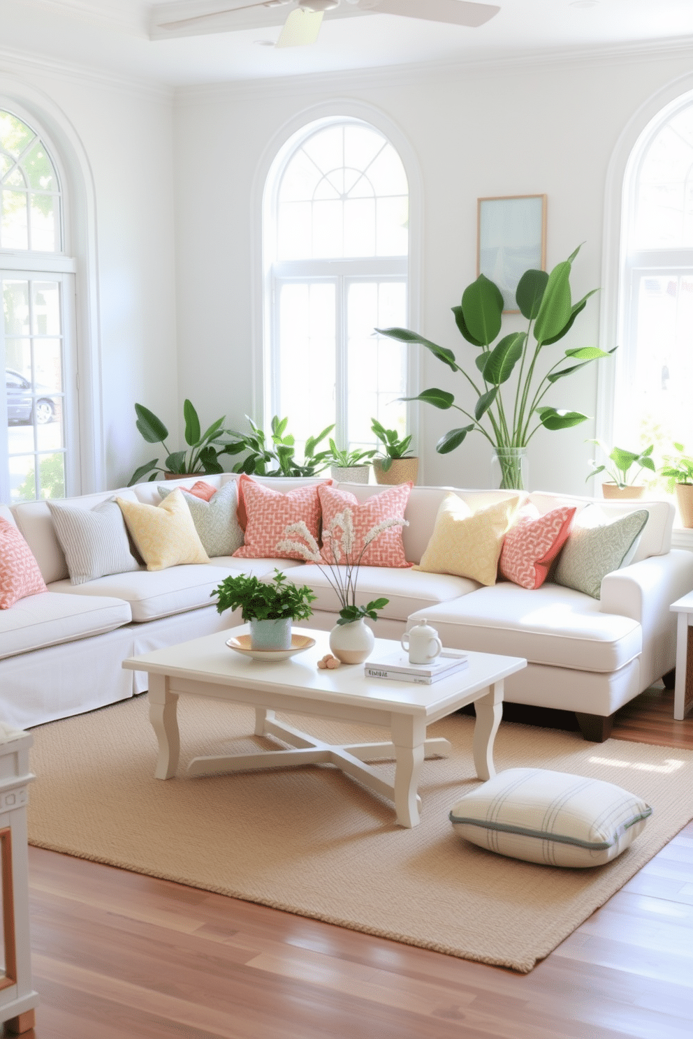 A bright and airy summer living room features a light-colored coffee table at the center, surrounded by a plush sectional sofa adorned with colorful throw pillows. Large windows allow natural light to flood the space, highlighting the soft pastel hues of the decor and the fresh greenery of potted plants placed strategically around the room.