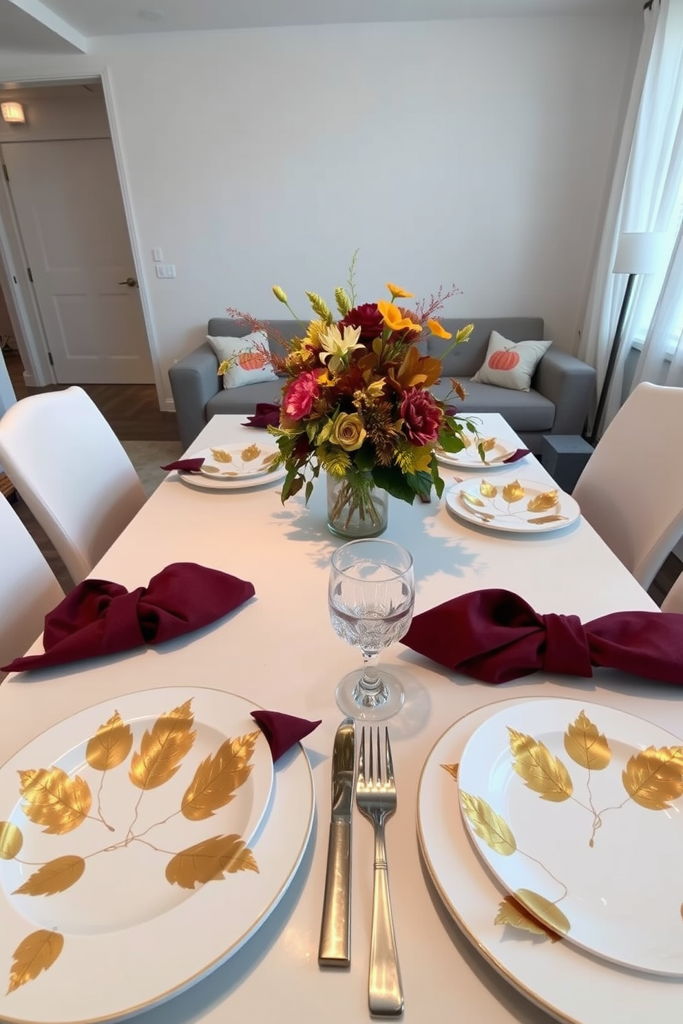 A beautifully set Thanksgiving table features elegant white plates adorned with golden leaf accents. Surrounding the table are rich burgundy napkins and a centerpiece of seasonal flowers in warm autumn hues. The apartment is decorated with subtle Thanksgiving touches, including pumpkin-themed cushions on the sofa. Soft, ambient lighting casts a cozy glow over the space, enhancing the festive atmosphere.