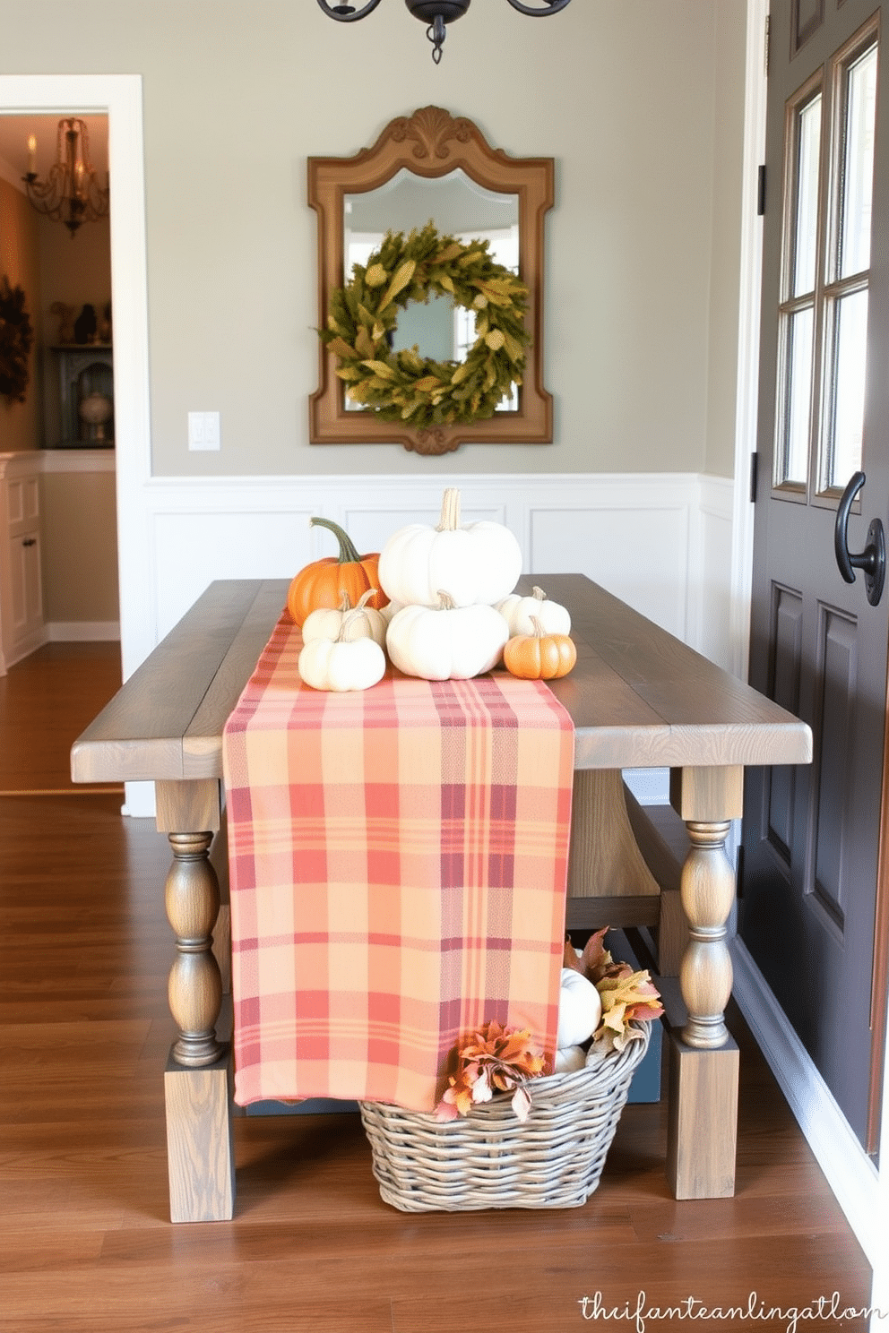 A warm plaid table runner is elegantly draped across a rustic wooden table, adorned with a collection of small pumpkins in varying sizes and colors. The entryway features a cozy atmosphere, enhanced by soft lighting and seasonal decorations that welcome guests into the home. On the wall, a vintage mirror reflects the charming decor, while a small basket filled with autumn leaves sits at the base of the table. The overall design exudes warmth and invites a festive spirit, perfect for Thanksgiving gatherings.