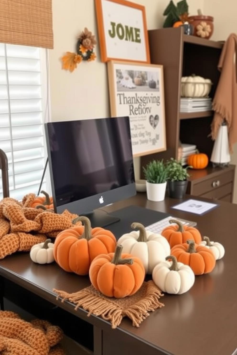 A cozy home office decorated for Thanksgiving features fabric pumpkins in various sizes and colors adorning the desk. The pumpkins are arranged alongside a warm, knitted throw and a small potted plant, creating an inviting workspace atmosphere.