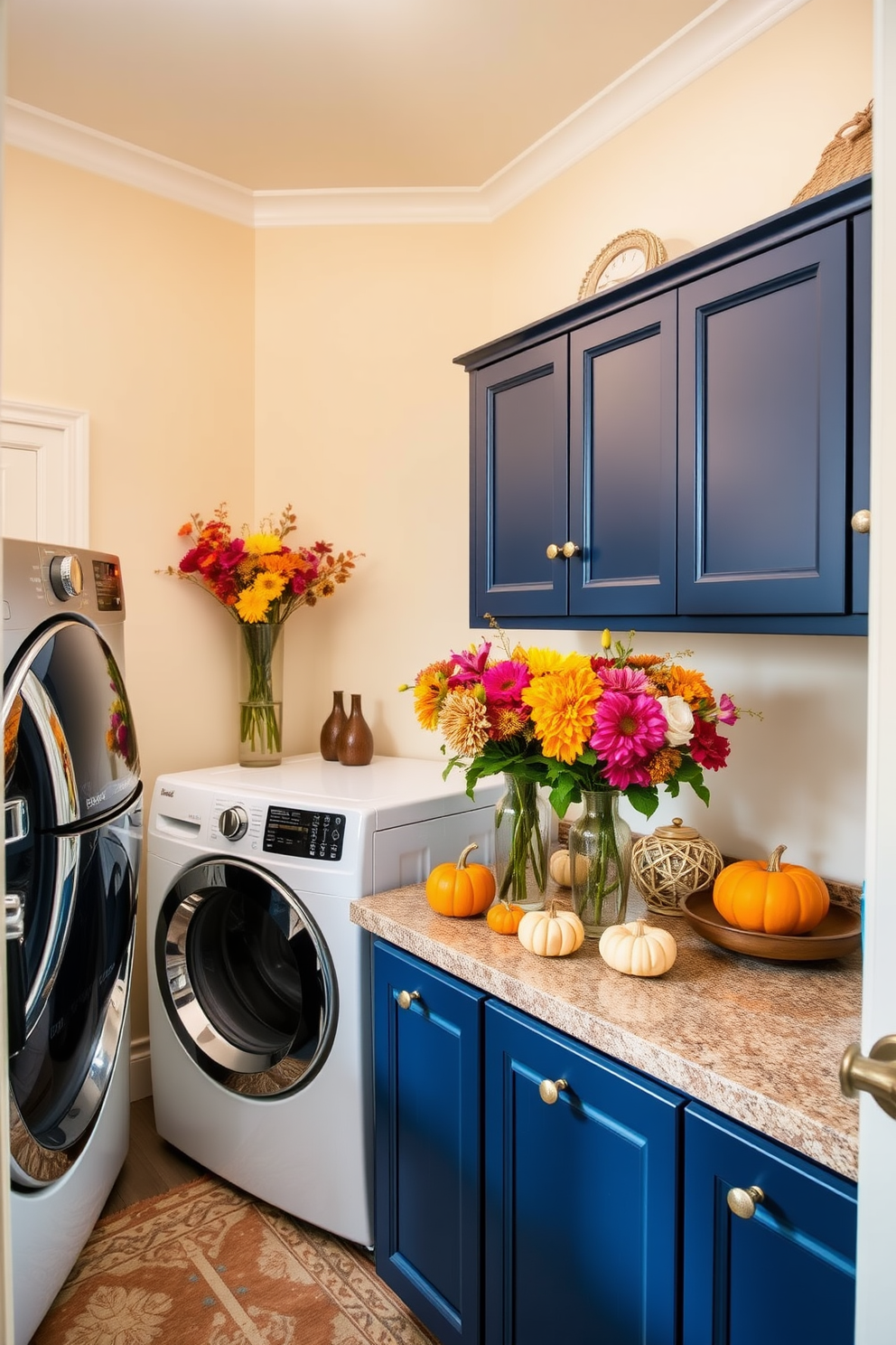 A vibrant laundry room adorned with colorful fall flowers in elegant vases. The walls are painted in a soft cream color, and the cabinetry features a rich navy blue finish, creating a warm and inviting atmosphere. On the countertop, decorative pumpkins and seasonal accents are arranged alongside the vases, adding a festive touch. The floor is covered with a stylish patterned rug that complements the overall color scheme, making the space both functional and aesthetically pleasing.