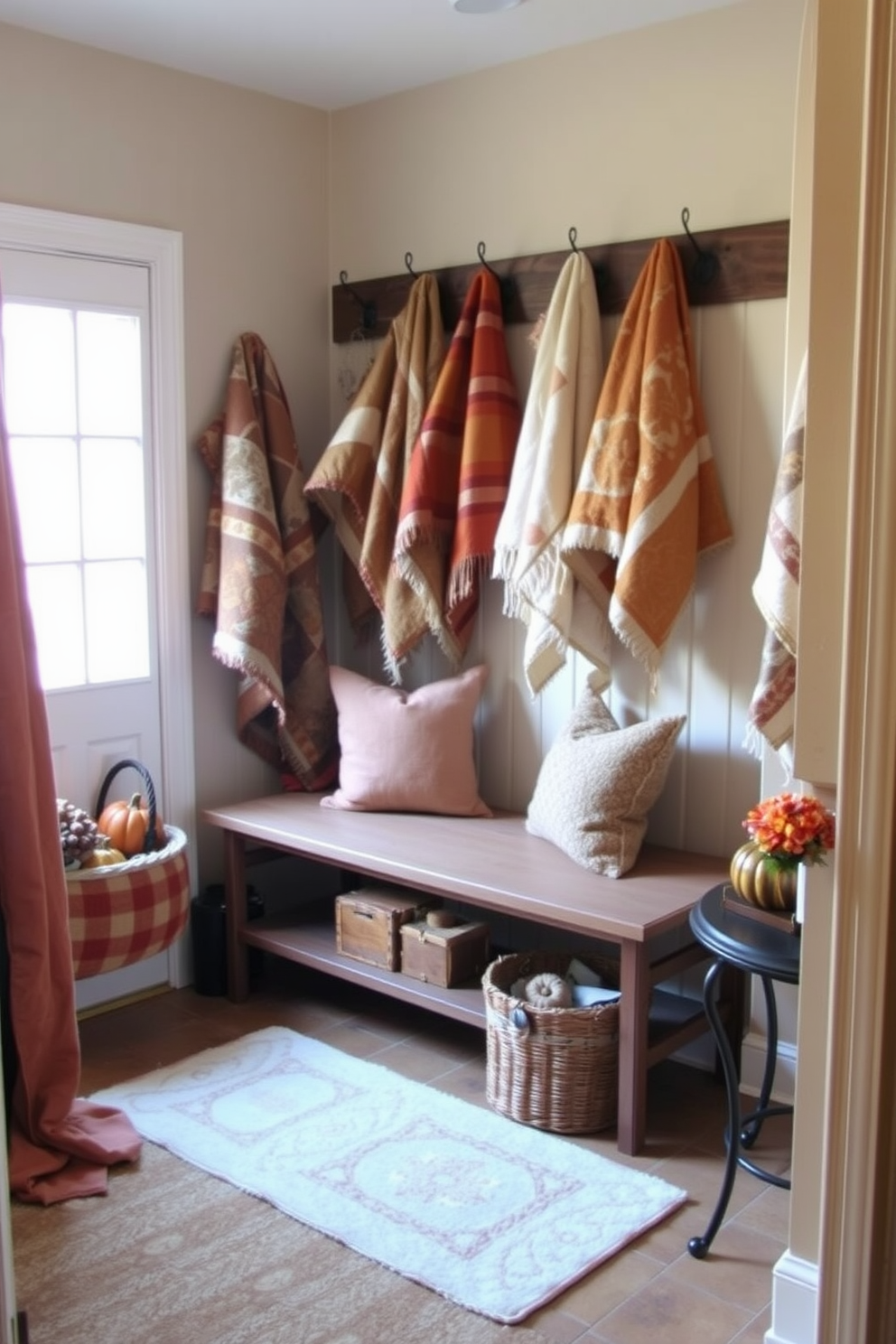 A cozy mudroom adorned with quilted throws in warm earth tones. The space features a bench with plush cushions and hooks for hanging jackets, creating a welcoming atmosphere for guests. Decorative elements include a rustic basket filled with seasonal items and a small table displaying autumn-themed decor. The walls are painted in a soft beige, complementing the rich textures of the throws and enhancing the overall warmth of the room.