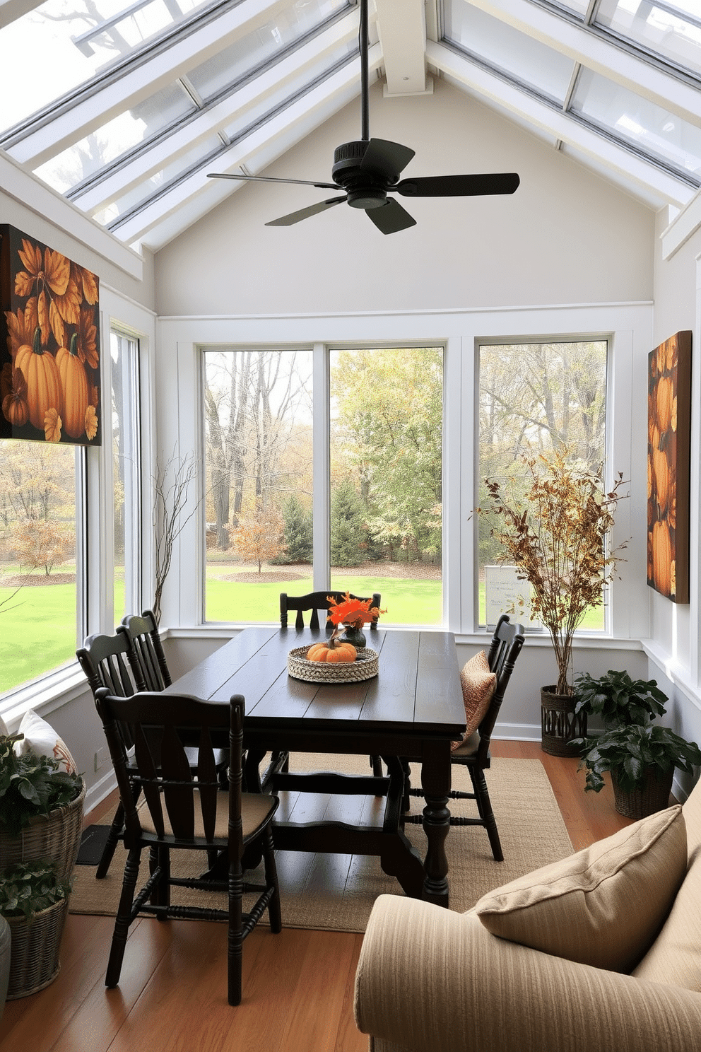 A cozy sunroom adorned with harvest-themed wall art featuring vibrant autumn leaves and pumpkins. The space is filled with natural light, showcasing a rustic wooden table surrounded by comfortable chairs, perfect for family gatherings during Thanksgiving.