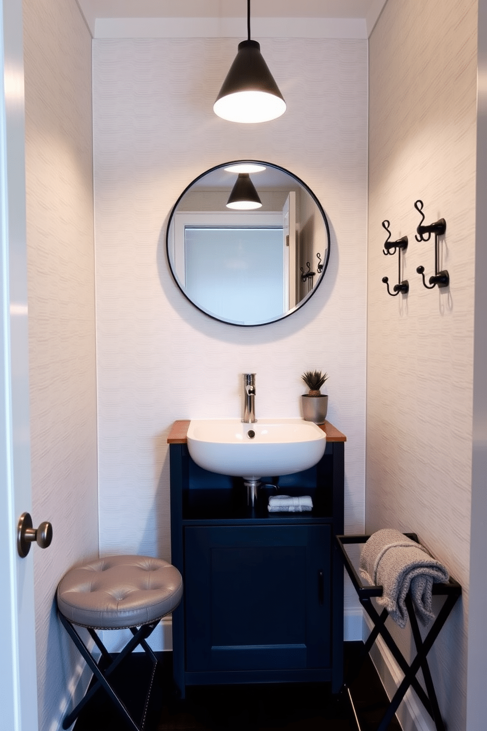 A chic tiny powder room featuring a sleek, wall-mounted sink with a compact storage cabinet underneath. The walls are adorned with a light, textured wallpaper, and a stylish round mirror reflects the soft glow of a pendant light above. Incorporating multi-functional furniture, a foldable vanity table doubles as a workspace when needed. A small, cushioned stool provides seating and can be tucked away to maximize space, while decorative hooks on the wall offer stylish storage for towels and accessories.