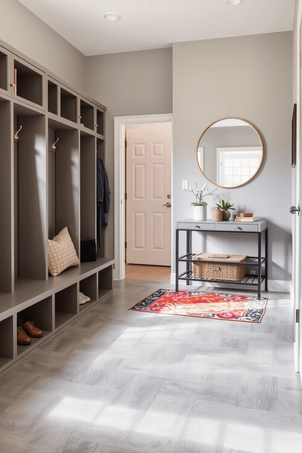 A functional mudroom designed for easy cleanup features durable flooring made of large ceramic tiles in a neutral gray tone. Built-in cubbies with hooks line the walls, providing storage for coats and bags, while a bench with a cushion offers a comfortable spot to sit while removing shoes. The entryway of the townhouse showcases a stylish yet practical design with a sleek console table against the wall. Above the table, a large round mirror reflects natural light, and a vibrant area rug adds a pop of color to the space, enhancing the welcoming atmosphere.