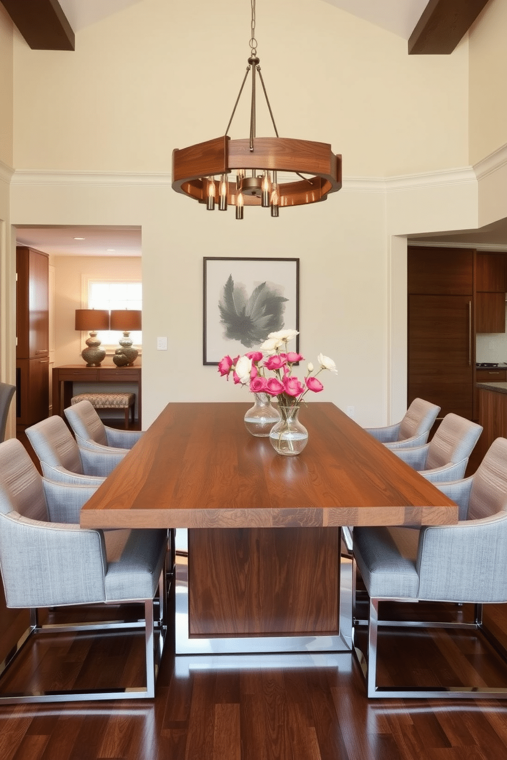 A transitional dining room featuring warm wood finishes paired with sleek metal accents. The table is a rich walnut with a polished chrome base, surrounded by upholstered chairs in a soft gray fabric. A statement chandelier with a mix of wood and metal elements hangs above the table, casting a warm glow. The walls are painted in a soft cream, complementing the natural tones of the wood and metal throughout the space.