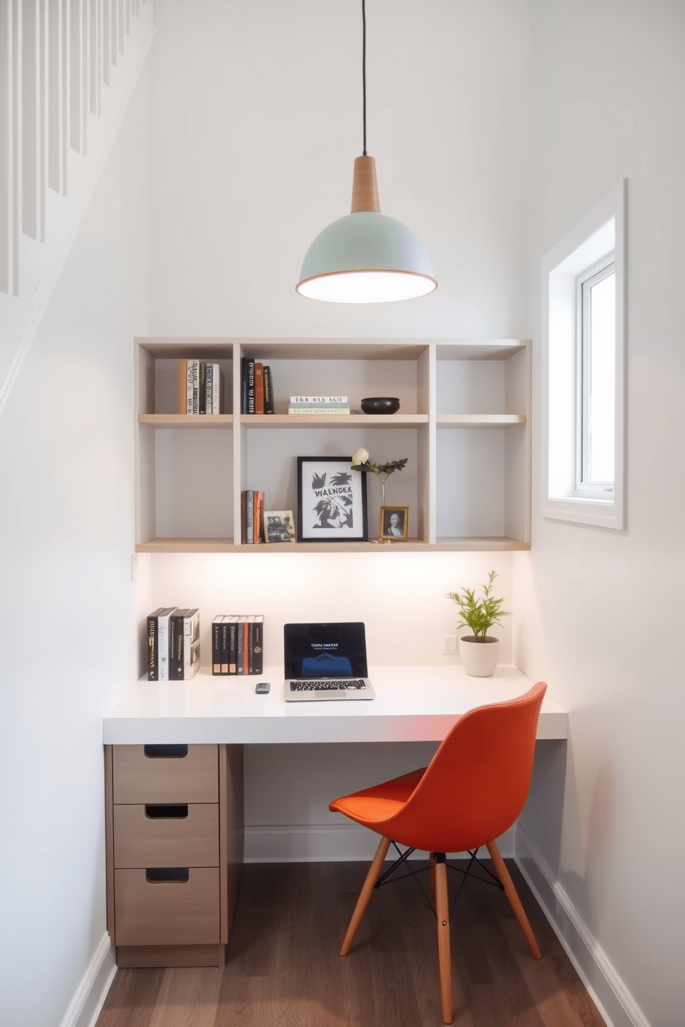 A compact home office nestled under the staircase features a sleek, modern desk with built-in storage. The walls are painted a soft white, and a stylish pendant light hangs above, illuminating the workspace. Incorporating shelves above the desk provides additional storage for books and decor. A comfortable chair with a pop of color adds personality to the space, while a small indoor plant brings a touch of nature.