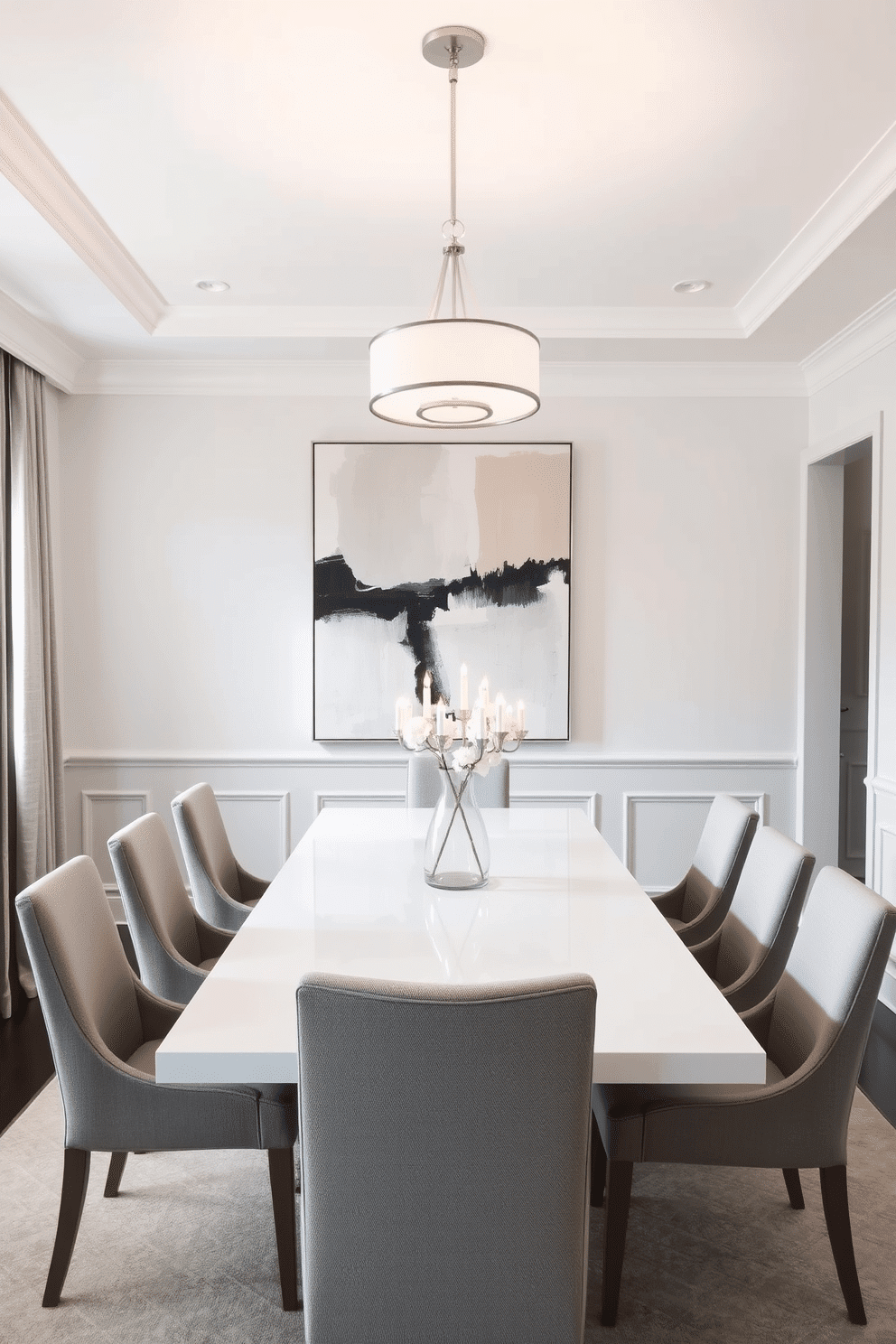 A sophisticated dining room featuring a white and gray color palette. The space includes a sleek rectangular dining table with gray upholstered chairs, illuminated by a modern chandelier above. The walls are adorned with subtle gray wainscoting, creating a refined backdrop. A large abstract painting in complementary tones hangs prominently, enhancing the room's elegance.