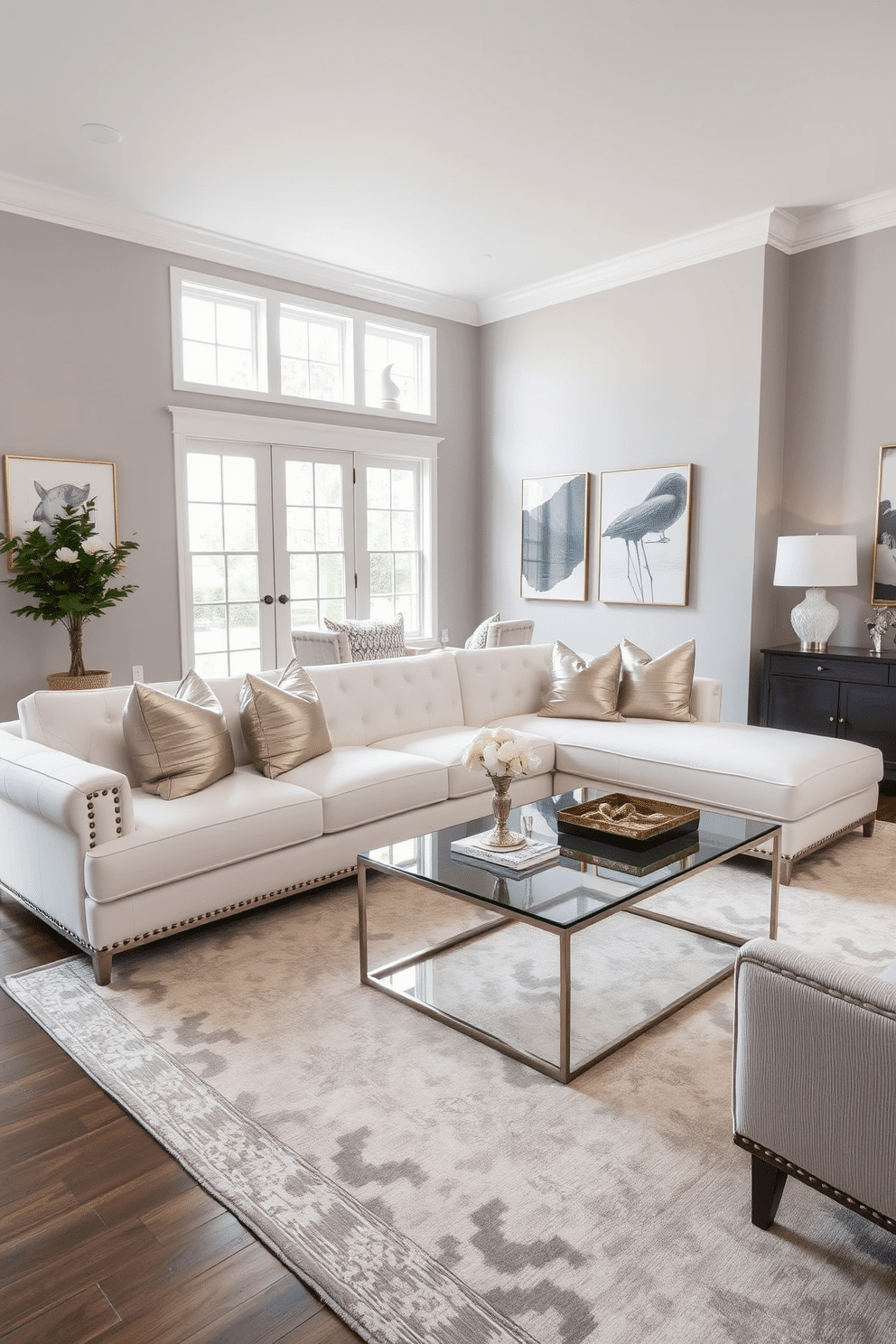 A luxe white sofa adorned with metallic throw pillows takes center stage in a spacious family room. The walls are painted in a soft gray, complementing the elegant decor and enhancing the room's airy feel. A large area rug in neutral tones anchors the seating area, while a modern coffee table with a glass top adds a touch of sophistication. Floor-to-ceiling windows allow natural light to flood the space, highlighting the carefully curated artwork on the walls.