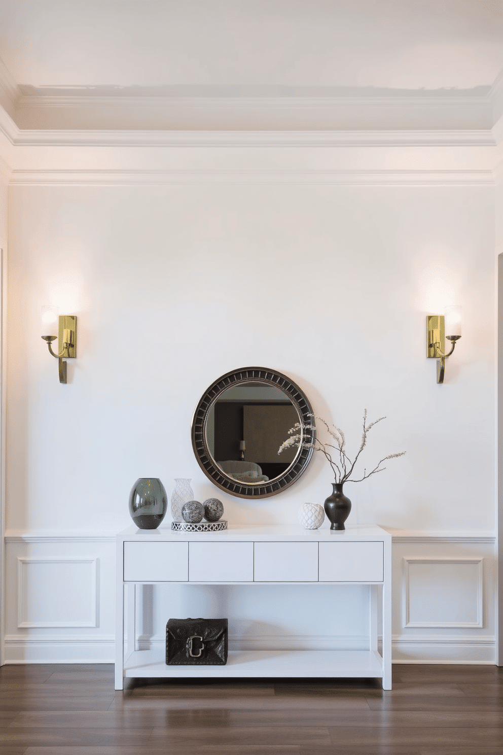 A bright and inviting foyer with layered lighting, featuring elegant wall sconces that cast a warm glow. The walls are painted in a soft white hue, complemented by a sleek console table adorned with decorative accents and a stylish mirror above it.