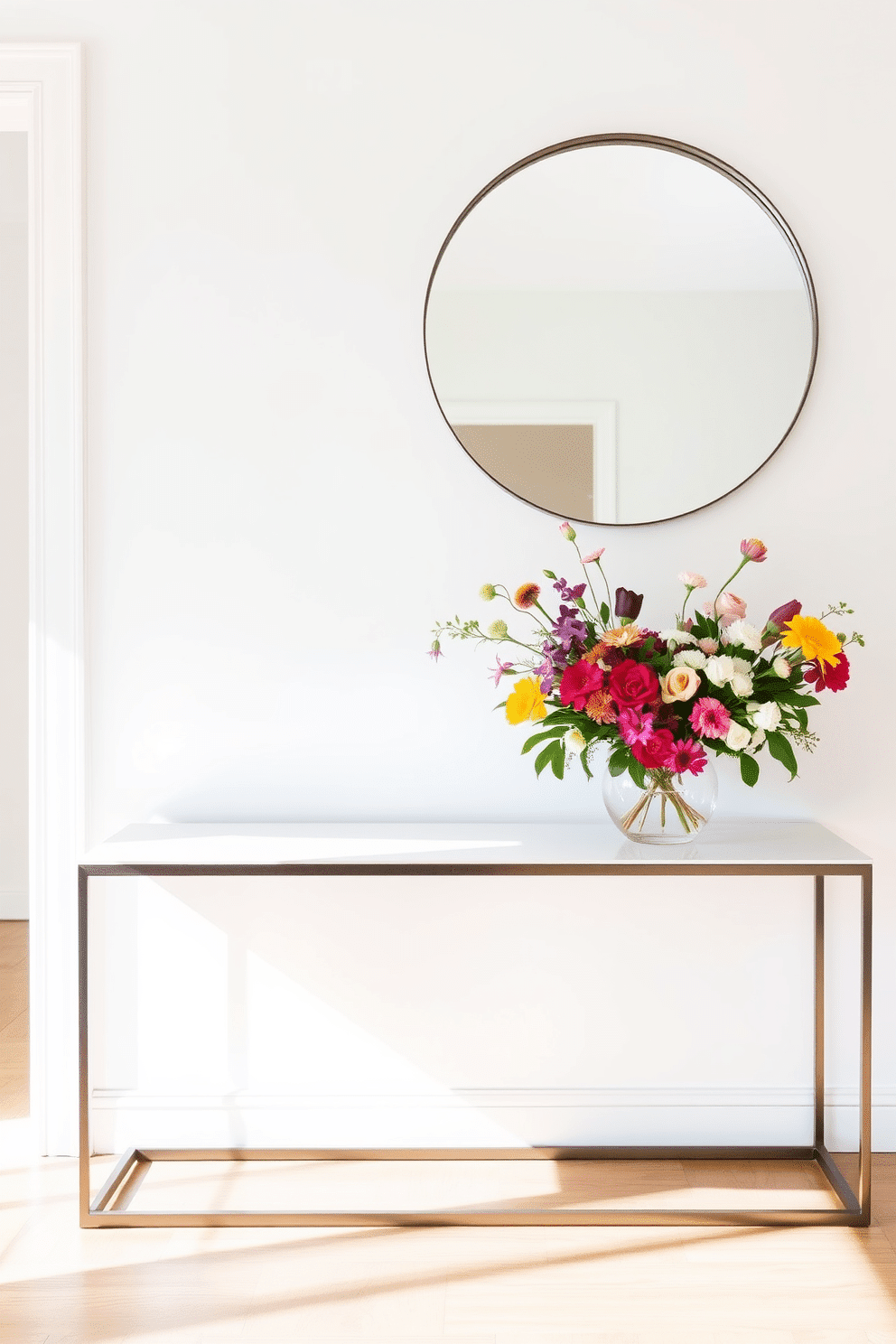 A sleek console table is positioned against a crisp white wall, adorned with a vibrant arrangement of fresh flowers in a modern vase. The floor is finished with light hardwood, and a large round mirror hangs above the table, reflecting natural light that floods the space.