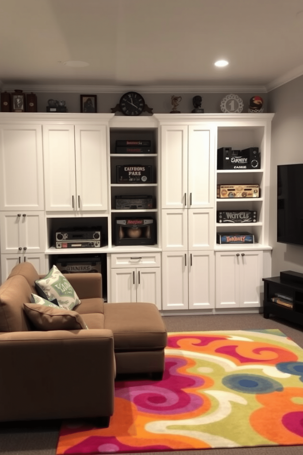 A stylish game room featuring white cabinetry that provides organized storage for board games and gaming equipment. The space is accented with a plush sectional sofa and a large flat-screen TV, creating an inviting atmosphere for entertainment. The walls are painted in a soft gray, complementing the sleek white cabinetry. A vibrant area rug adds a pop of color, while shelves above the cabinetry display decorative items and trophies, enhancing the room's personality.