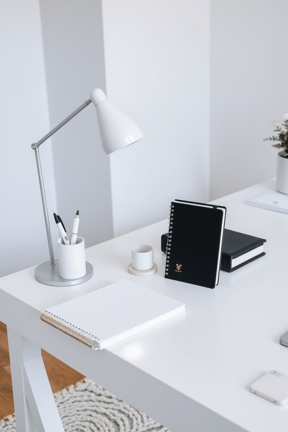 A stylish home office features elegant desk accessories in white tones, including a sleek pen holder, a minimalist desk lamp, and a textured notebook. The workspace is complemented by a white desk with clean lines, set against a backdrop of soft gray walls and a cozy area rug.