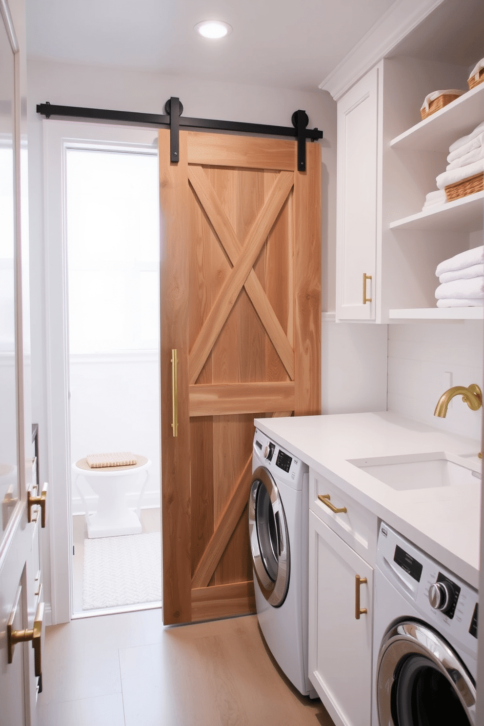 A bright and airy laundry room features a sliding barn door made of reclaimed wood, adding a modern touch to the space. The room is adorned with white cabinetry, providing ample storage, and a sleek countertop for folding clothes, complemented by stylish brass hardware.