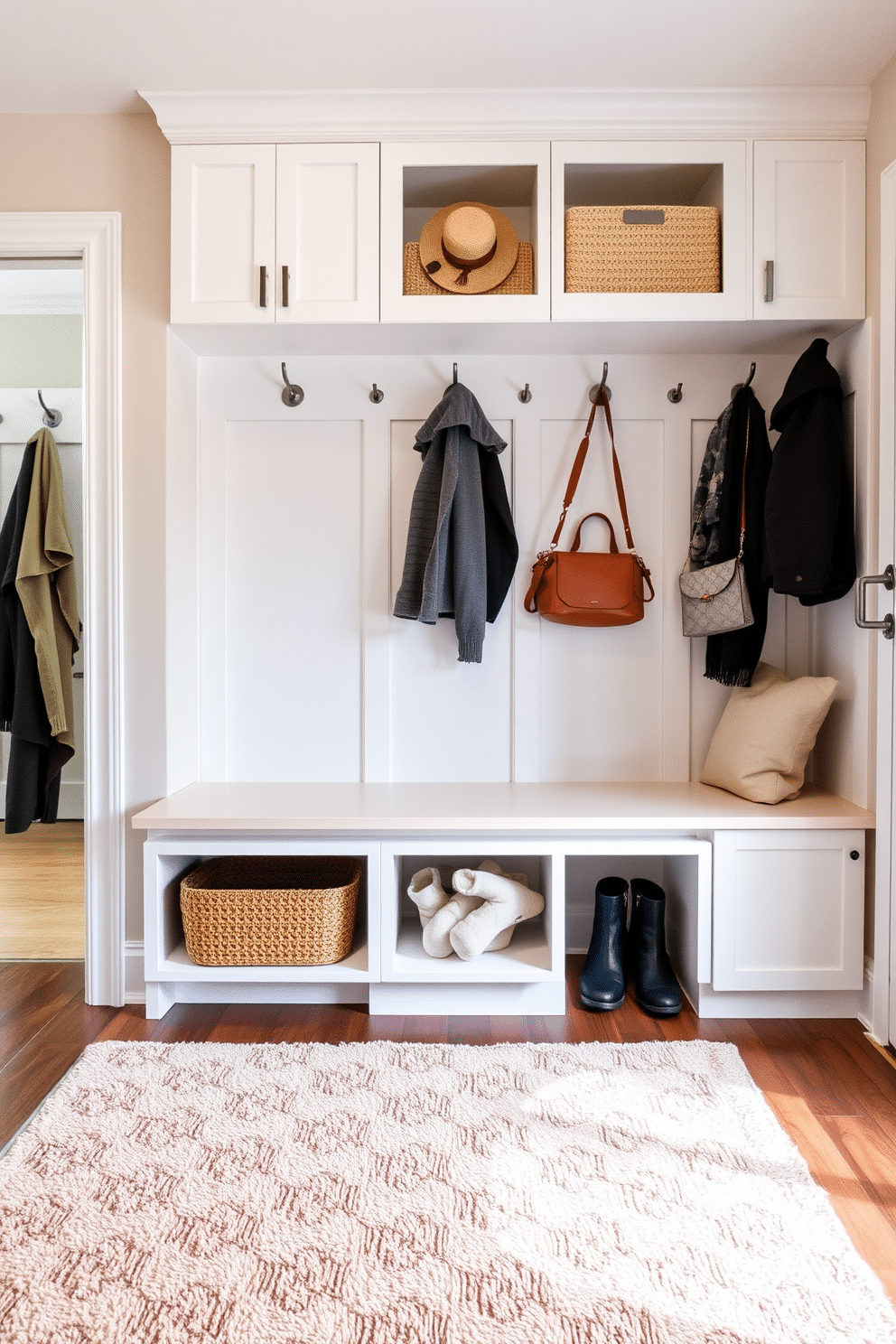 Cozy area rug to soften the space. The rug features a plush texture with a subtle geometric pattern in warm earth tones, creating a welcoming atmosphere in the room. White mudroom design ideas. The space includes built-in cabinetry with sleek white finishes, complemented by a durable bench with storage underneath, and hooks for hanging coats and bags.