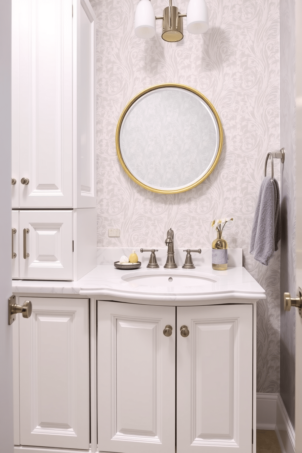 Bright white cabinetry with elegant hardware creates a fresh and inviting atmosphere in the powder room. The cabinetry features intricate detailing and polished chrome handles, perfectly complementing the sleek marble countertop. The walls are adorned with a soft gray wallpaper that adds texture without overwhelming the space. A chic round mirror with a gold frame hangs above the stylish pedestal sink, enhancing the room's elegance and sophistication.