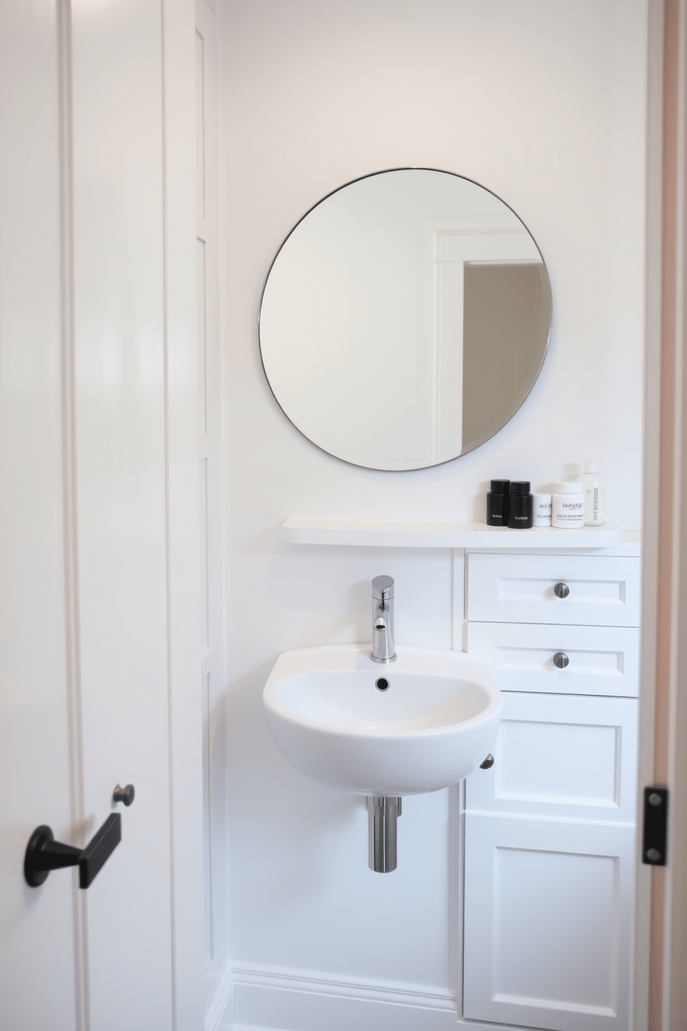 A compact yet stylish white powder room features a wall-mounted sink with a sleek, minimalist faucet. Above the sink, a large round mirror enhances the sense of space, while a small shelf below holds neatly arranged toiletries. Functional storage solutions are cleverly integrated into this small area, with built-in cabinets that blend seamlessly into the wall. The cabinets are painted in a soft white, complementing the overall bright and airy aesthetic of the room.