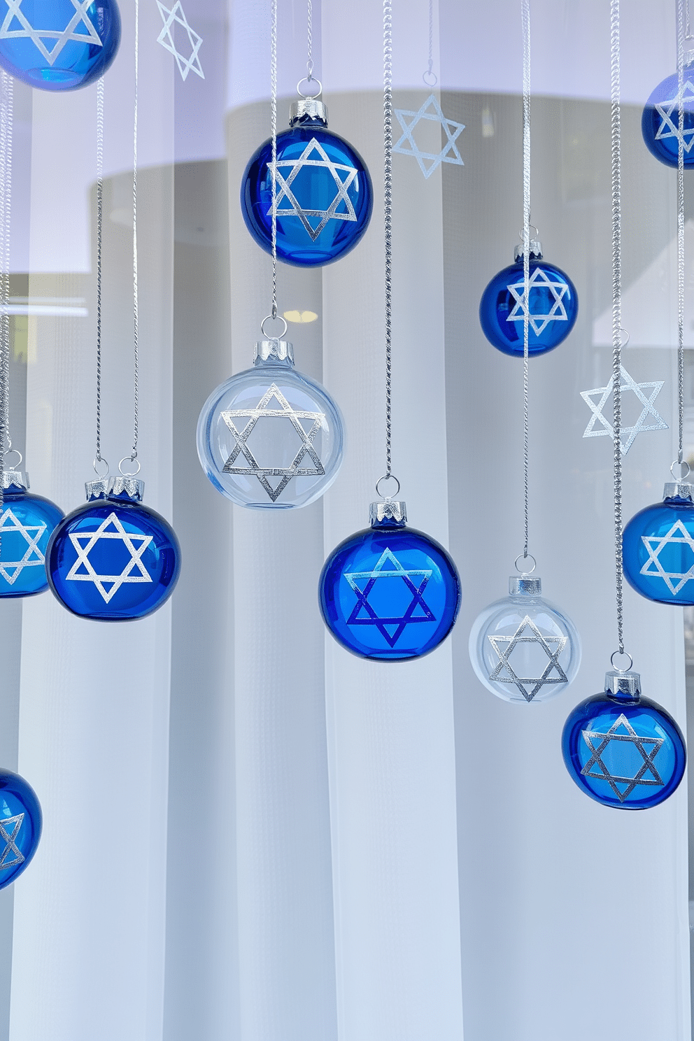 A festive window display adorned with hanging glass ornaments featuring intricate Hanukkah symbols. The ornaments, in shades of blue and silver, catch the light beautifully, creating a shimmering effect against the backdrop of a soft white curtain.