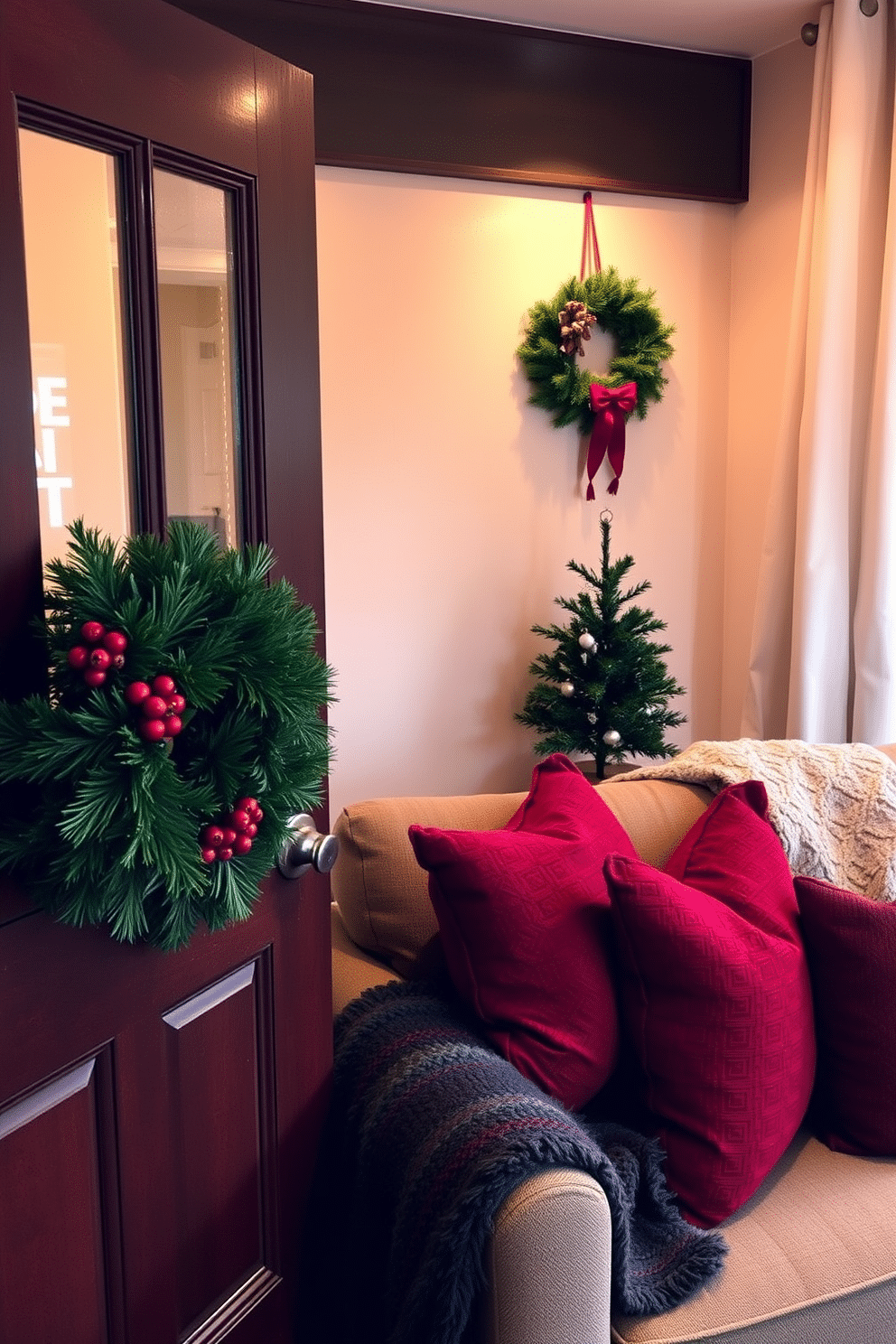 A cozy winter apartment decorated for the season. The front door features a lush evergreen wreath adorned with red berries and pinecones, while a matching smaller wreath hangs on the living room wall. Soft, warm lighting creates an inviting atmosphere throughout the space. Plush throws and pillows in deep reds and greens are arranged on the sofa, complemented by a small decorative tree in the corner.