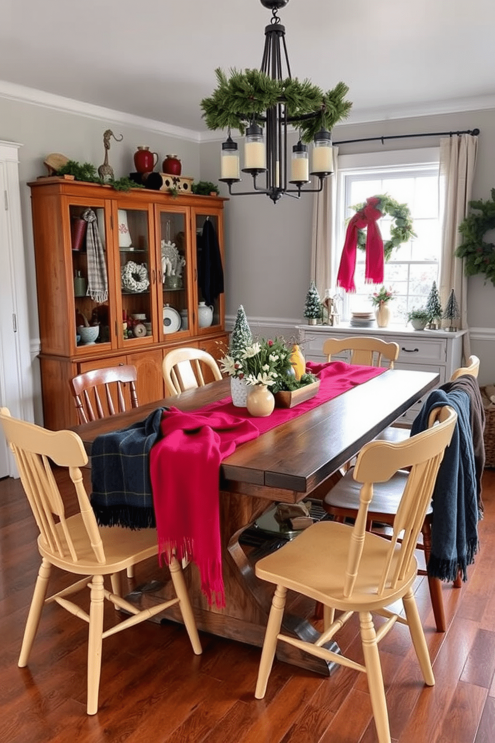 A cozy winter dining room featuring a rustic wooden table adorned with vibrant scarves used as tablecloths. Surrounding the table are mismatched chairs in warm tones, creating an inviting atmosphere filled with seasonal decorations.