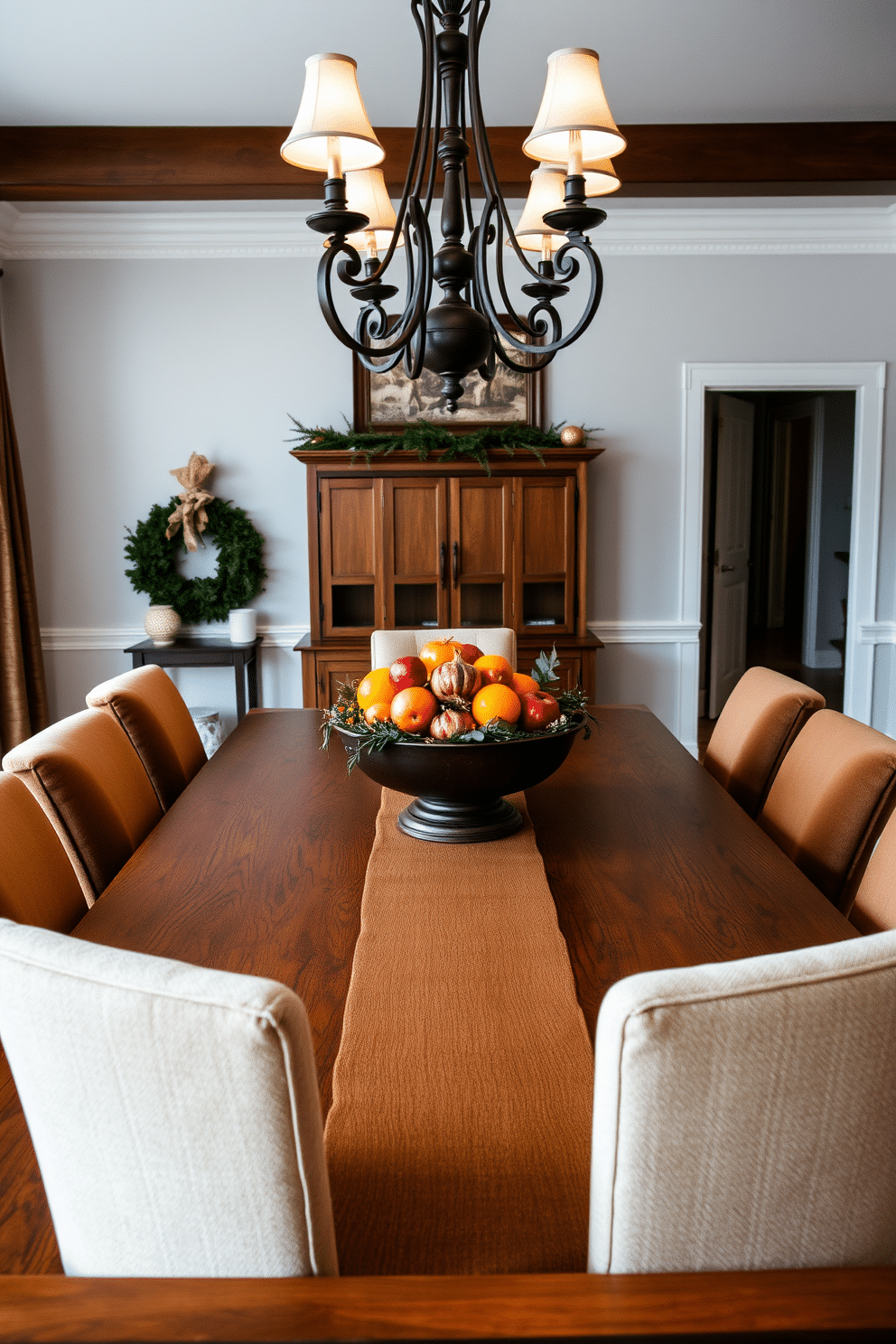 A cozy winter dining room features a large wooden table adorned with a vibrant seasonal fruit bowl at its center. The bowl is filled with oranges, pomegranates, and apples, creating a warm and inviting focal point for the space. Surrounding the table are plush upholstered chairs in rich earth tones, complemented by a soft, textured table runner. Soft, ambient lighting from a chandelier above enhances the inviting atmosphere, making it perfect for family gatherings.