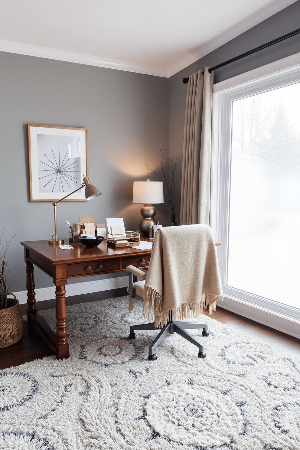 A cozy winter home office setting featuring a large wooden desk adorned with decorative trays for organization. The desk holds neatly arranged stationery, a stylish lamp, and a warm throw blanket draped over the chair. The walls are painted in a soft gray hue, complemented by a plush area rug in muted tones. A large window allows natural light to flood the space, with frosted glass accents adding a touch of elegance.